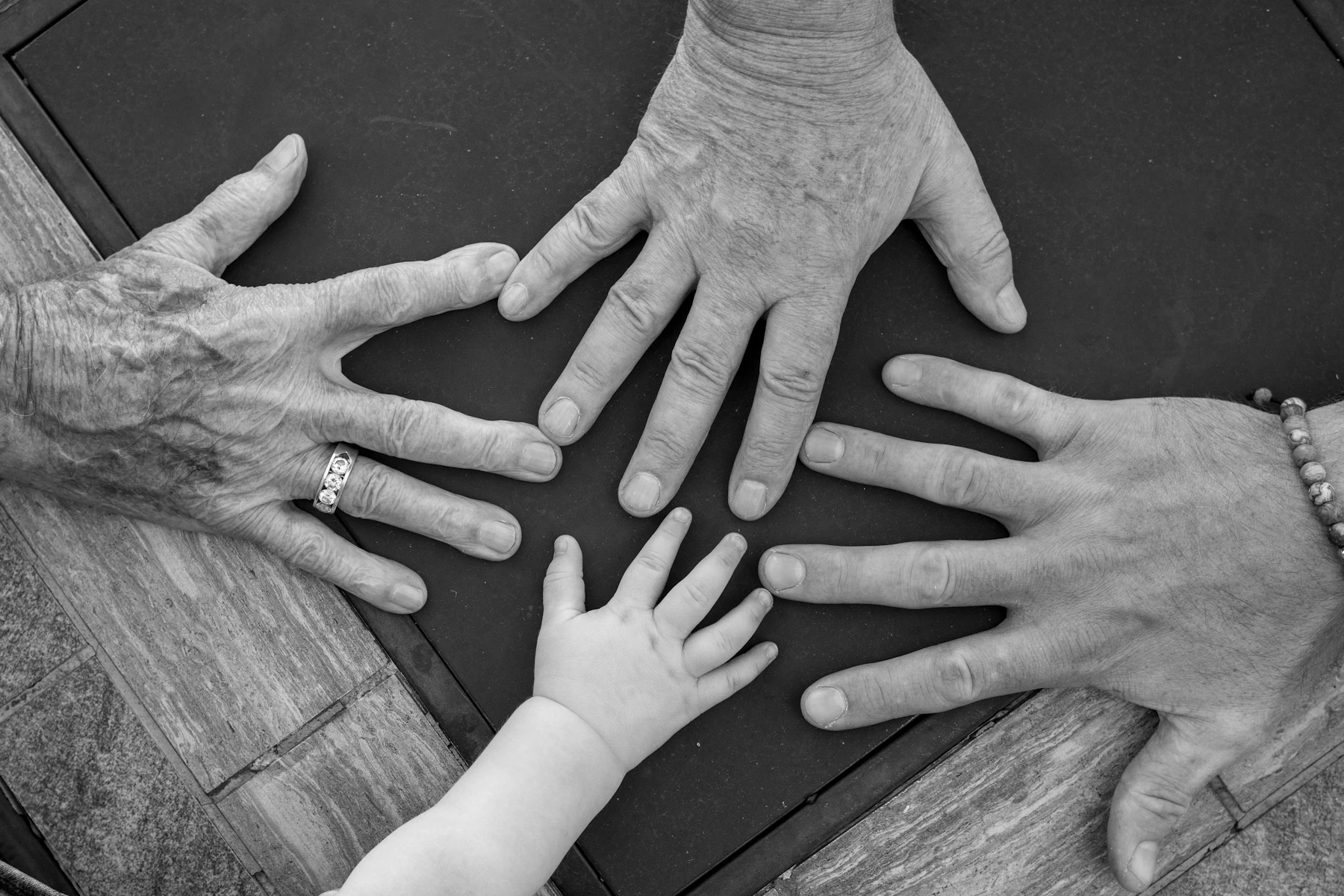 Four generations of hands resting together on a table