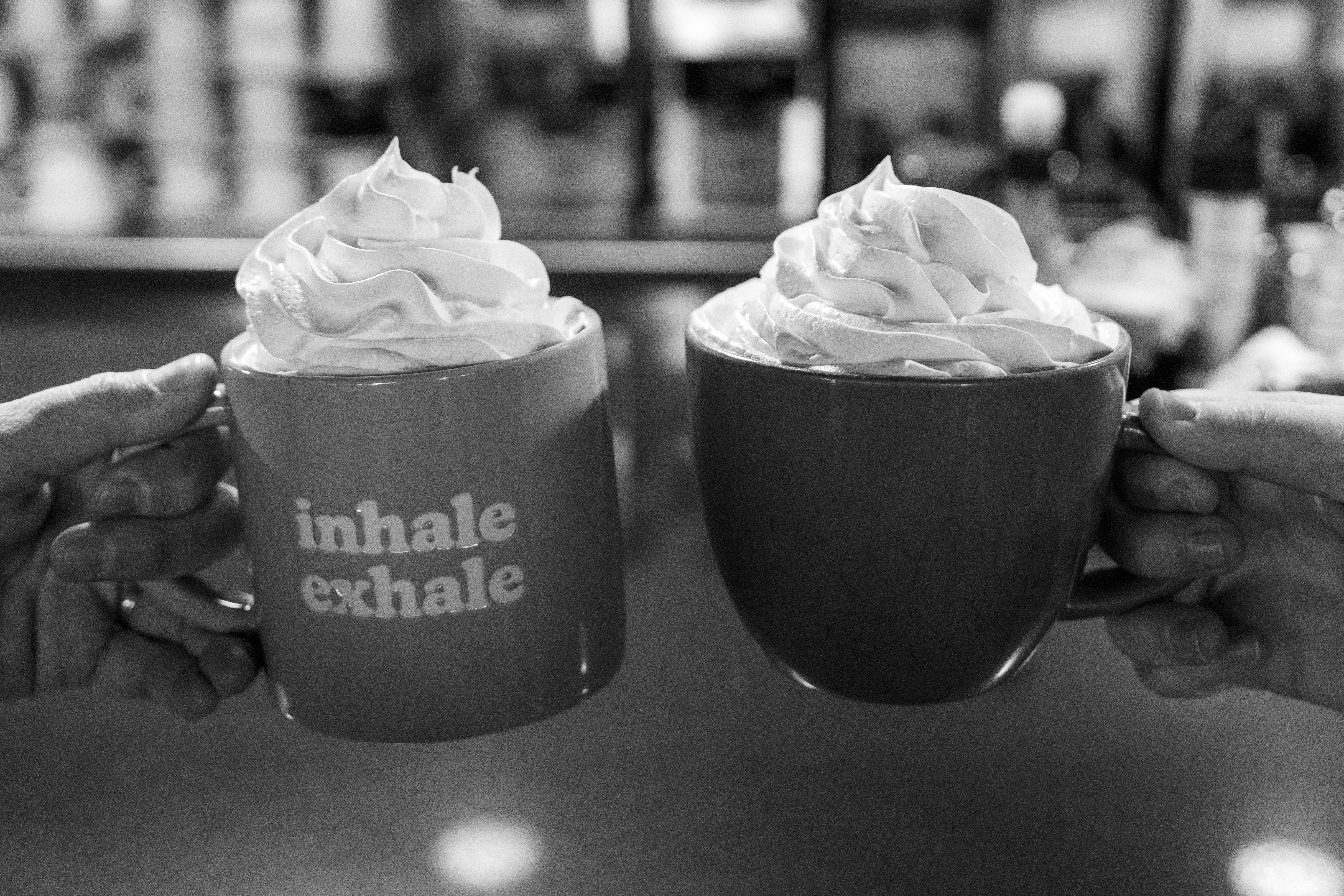 Two mugs with whipped cream and text