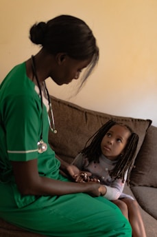 Nurse comforting a young child on a sofa.