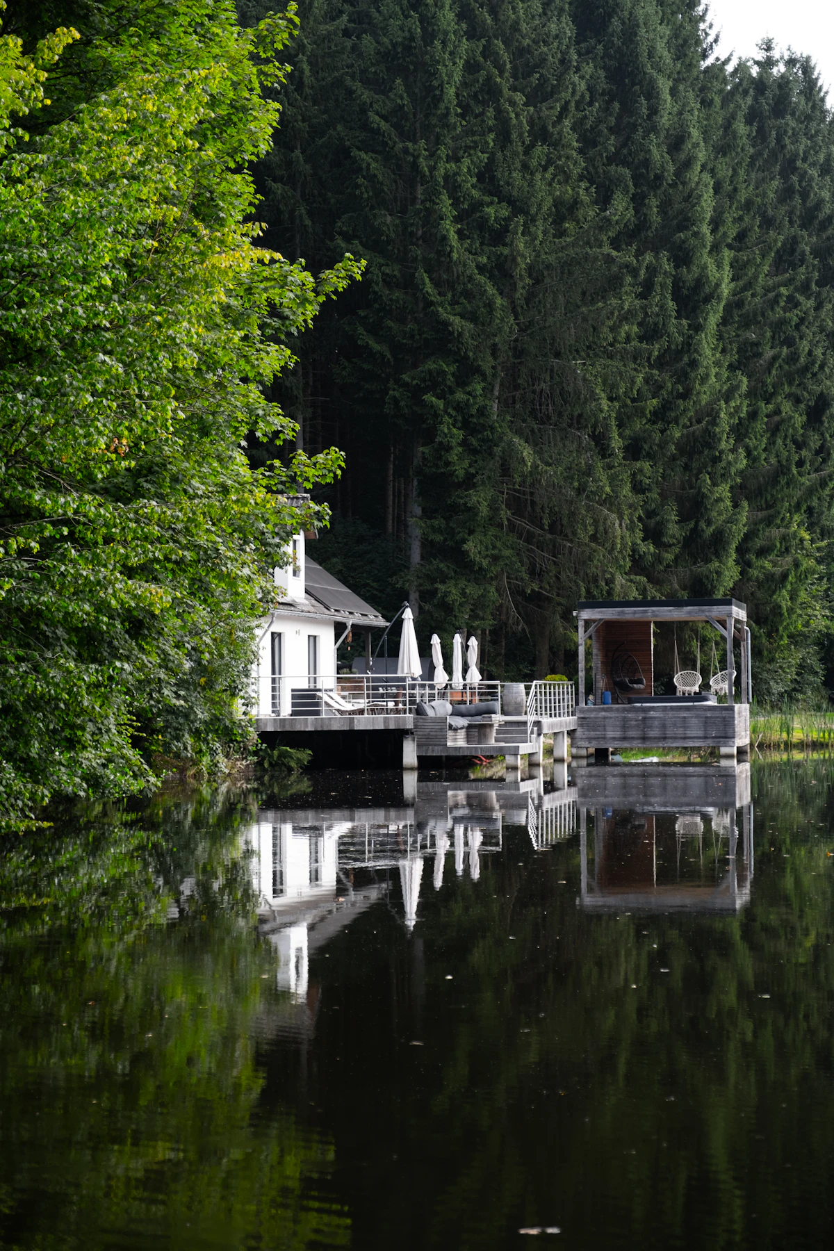 Lake house deck with glass railing reflected in calm water