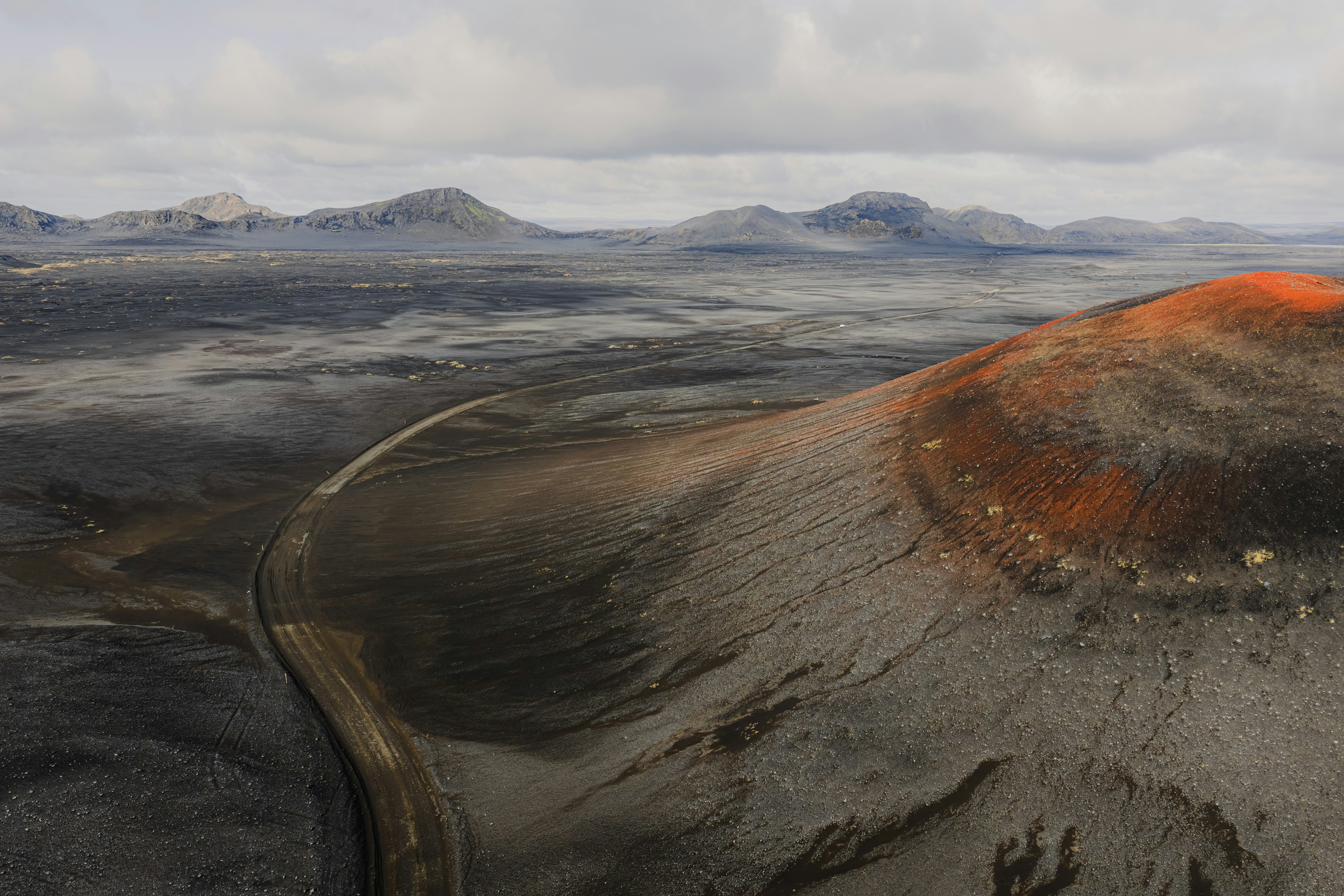 Volcanic landscape with a dirt road and red crater