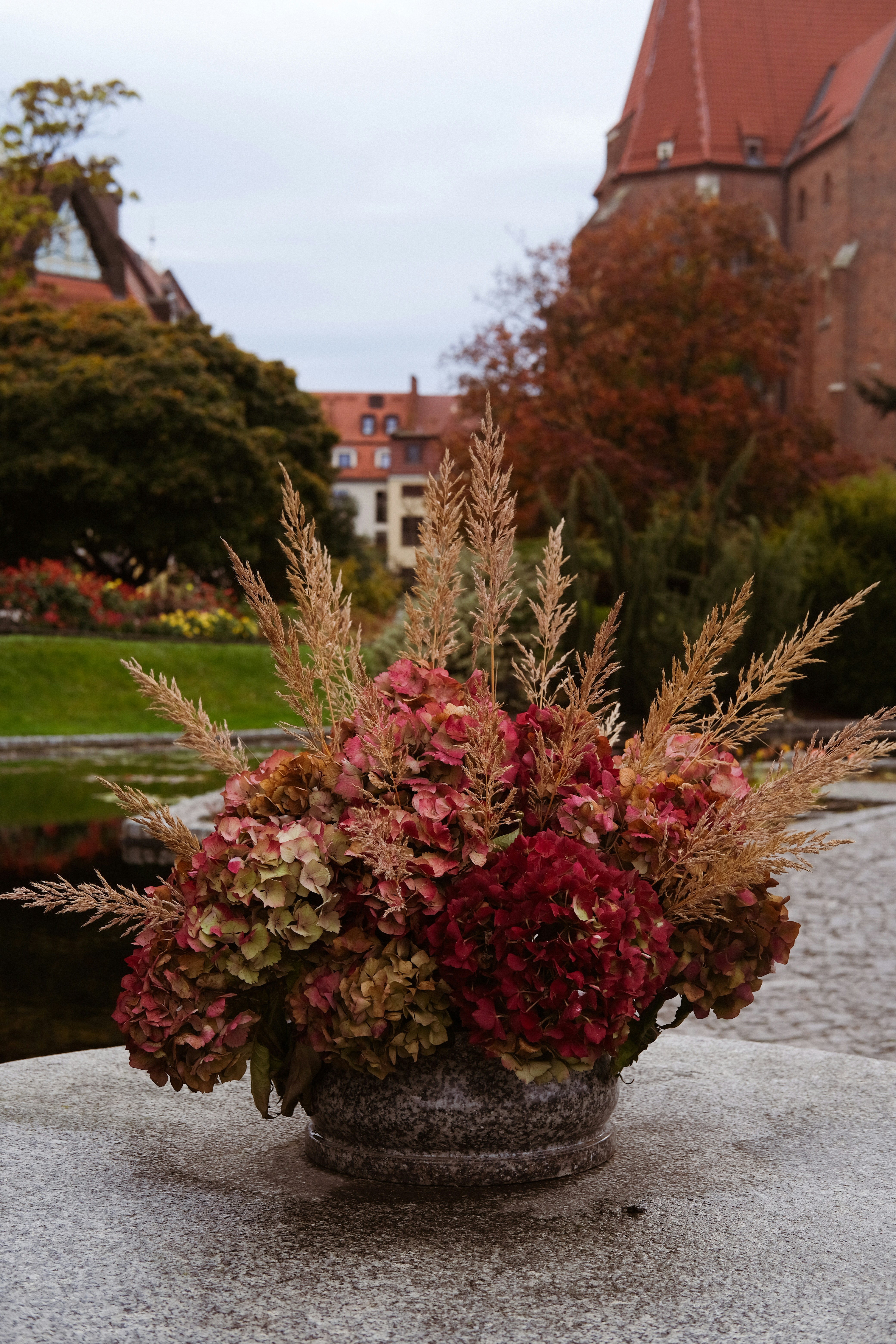 Getrocknete Hortensien und Gräser in einer Steinvase.