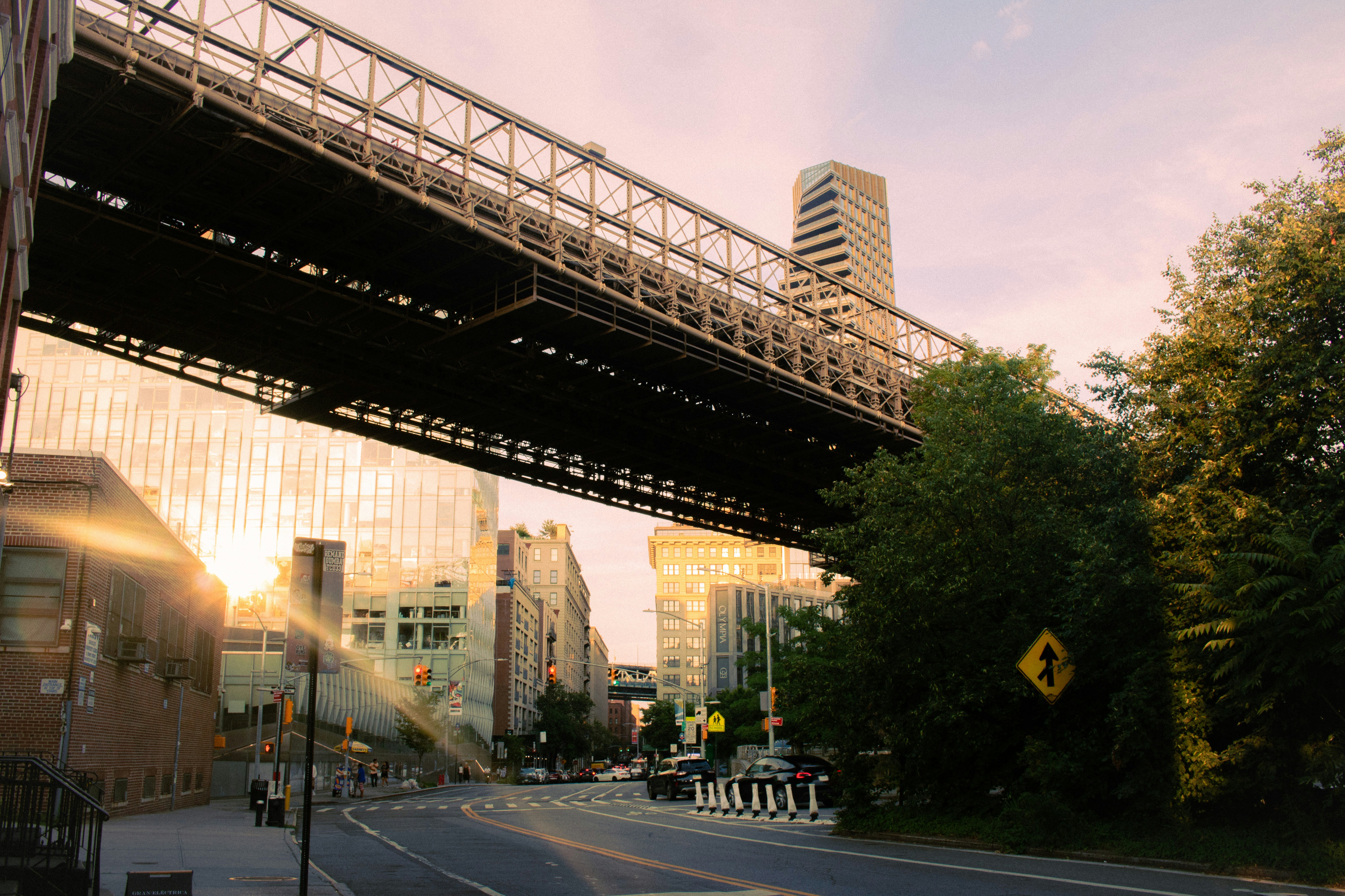 City street under a large bridge at sunset.