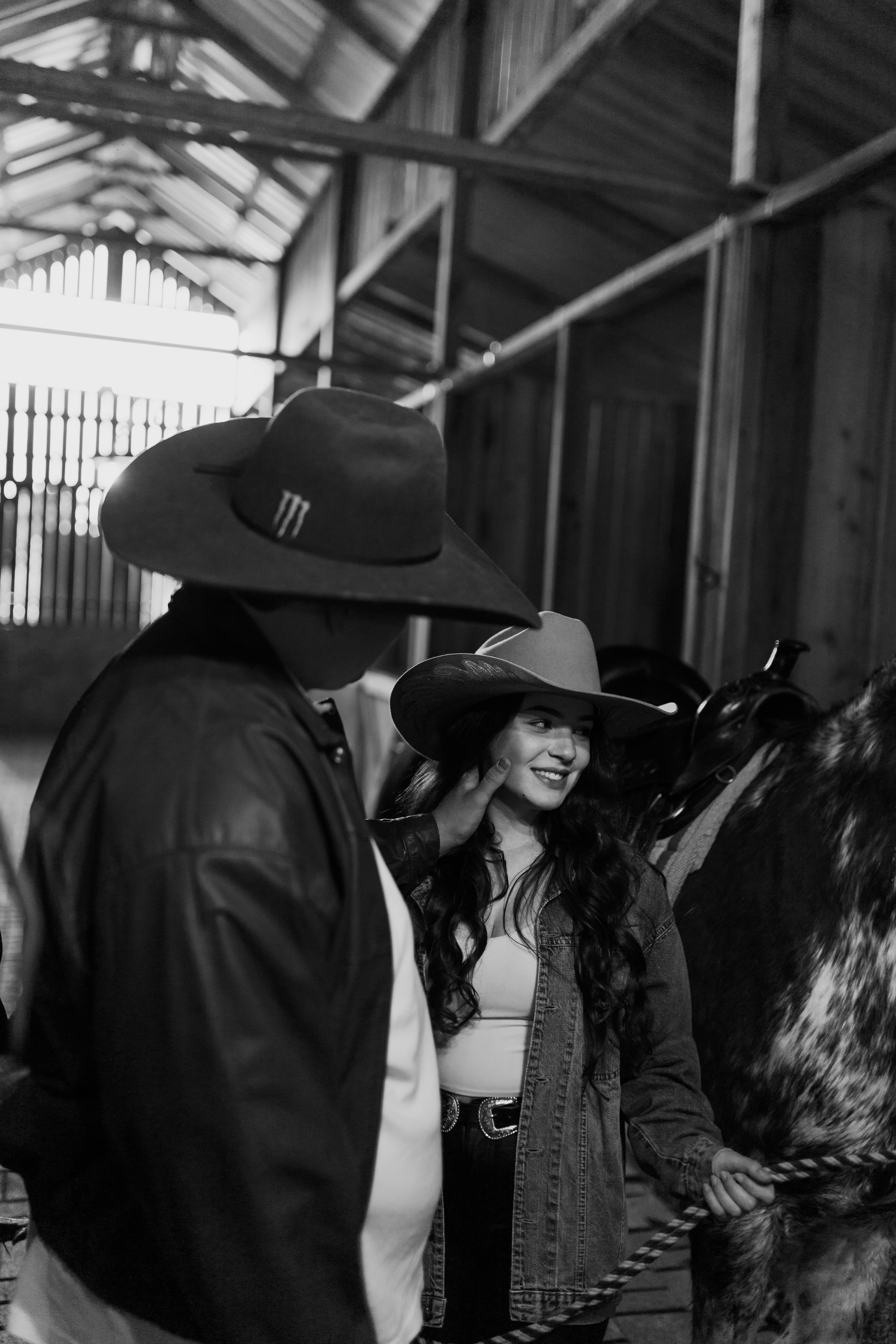 Couple in cowboy hats inside a barn.