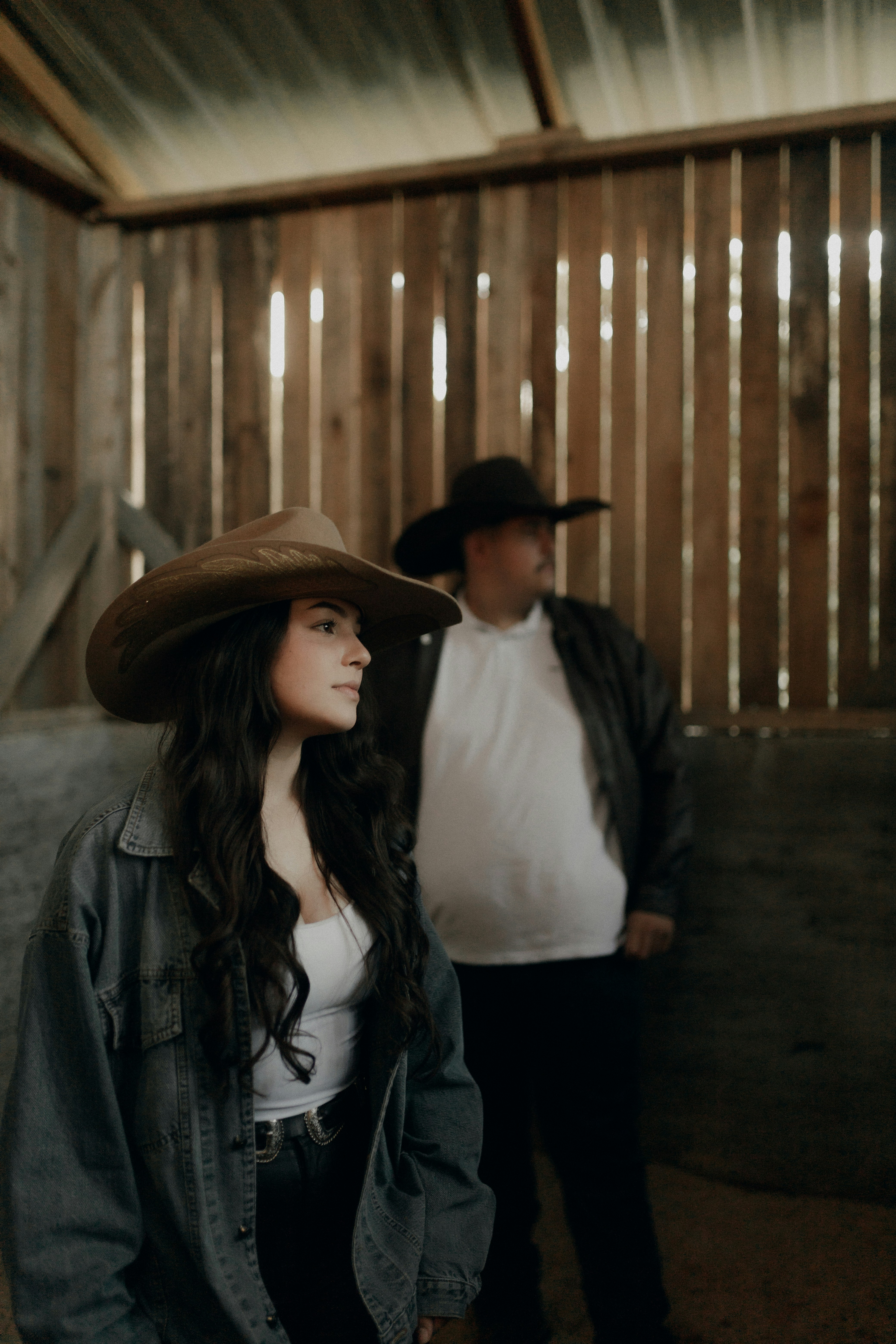 Couple in cowboy hats inside a rustic barn