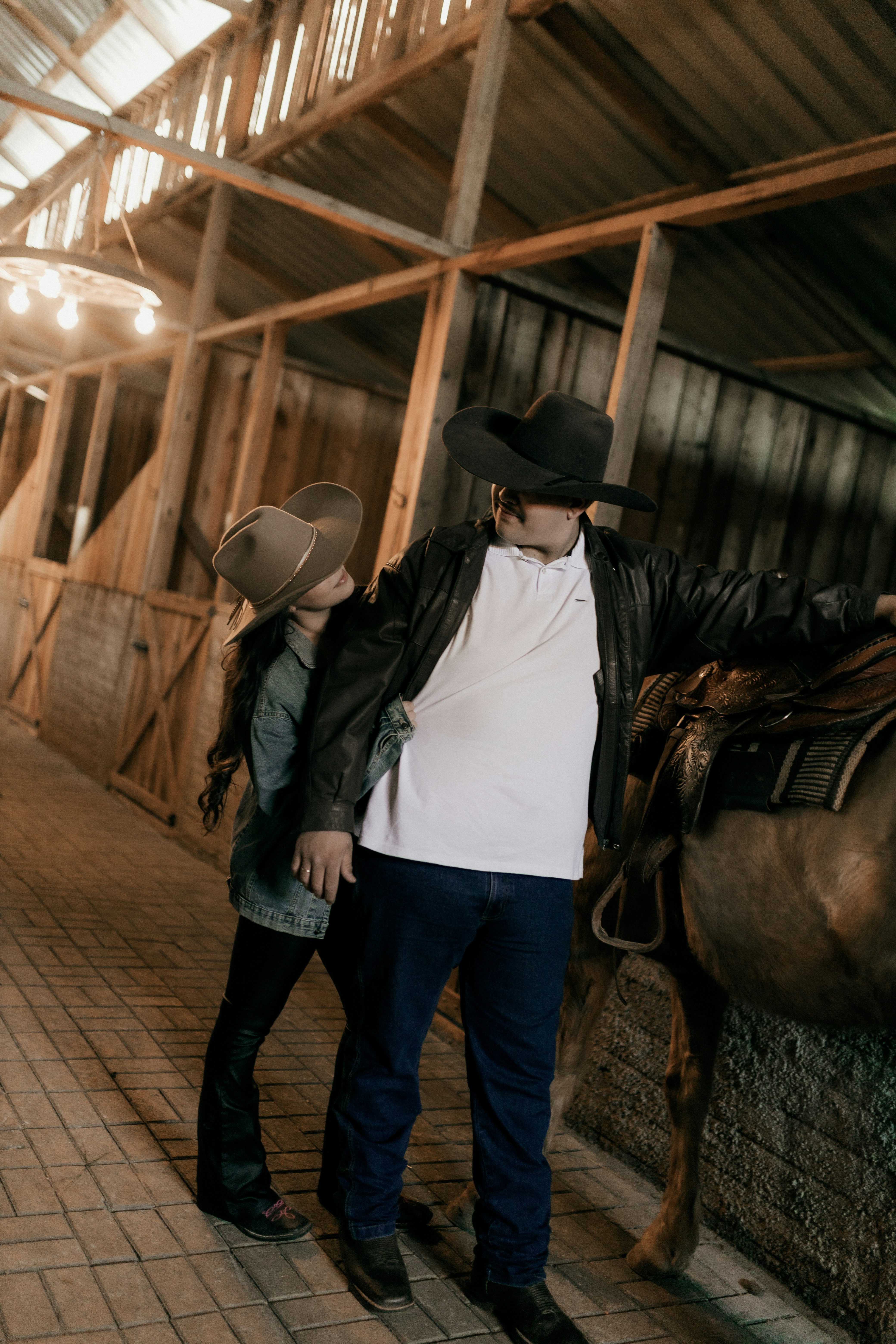 Couple in cowboy hats inside a rustic barn