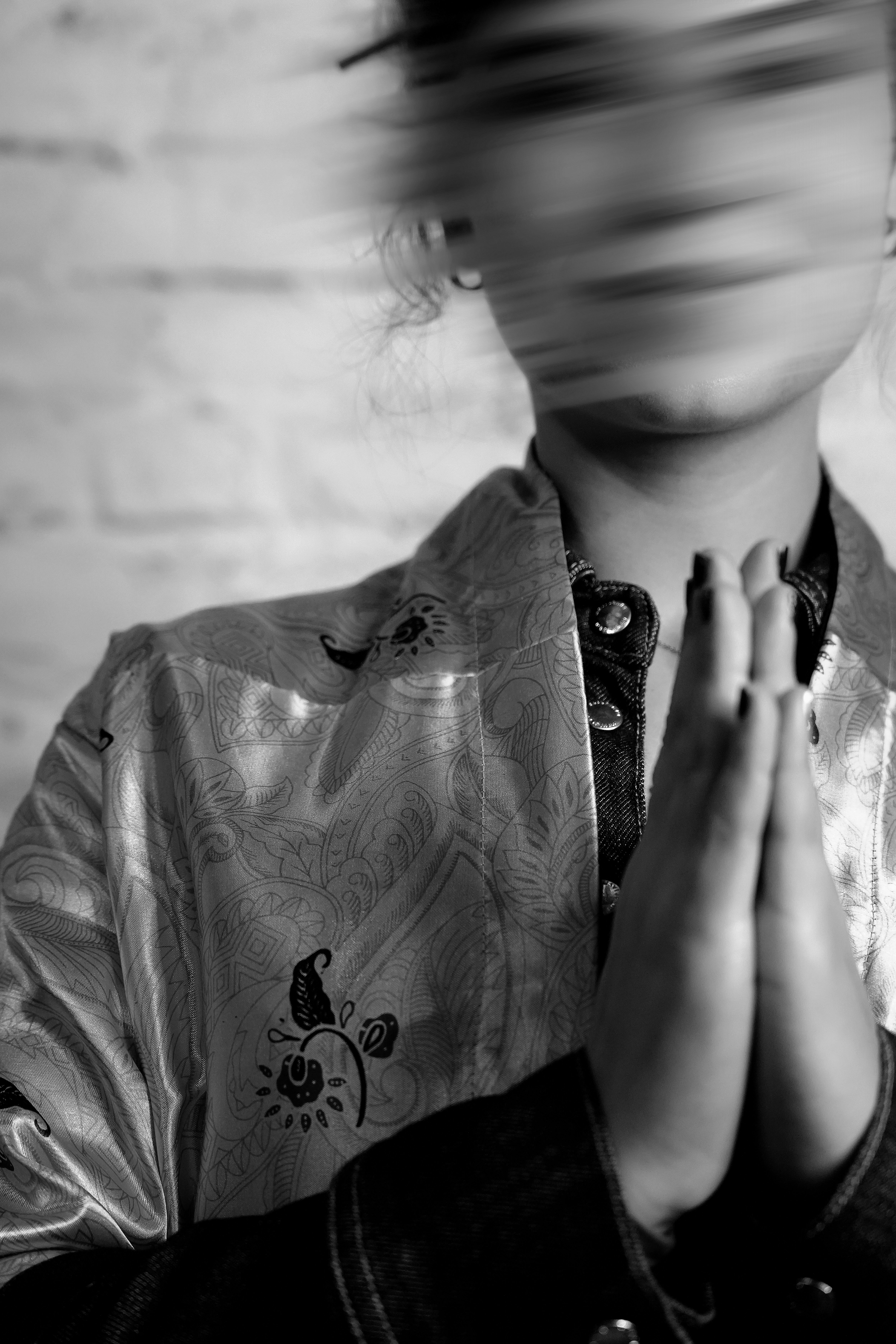 Volto sfocato di persona con le mani giunte