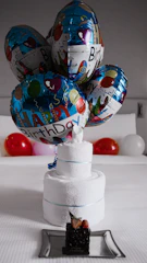 Birthday balloons and towel cake with small dessert.