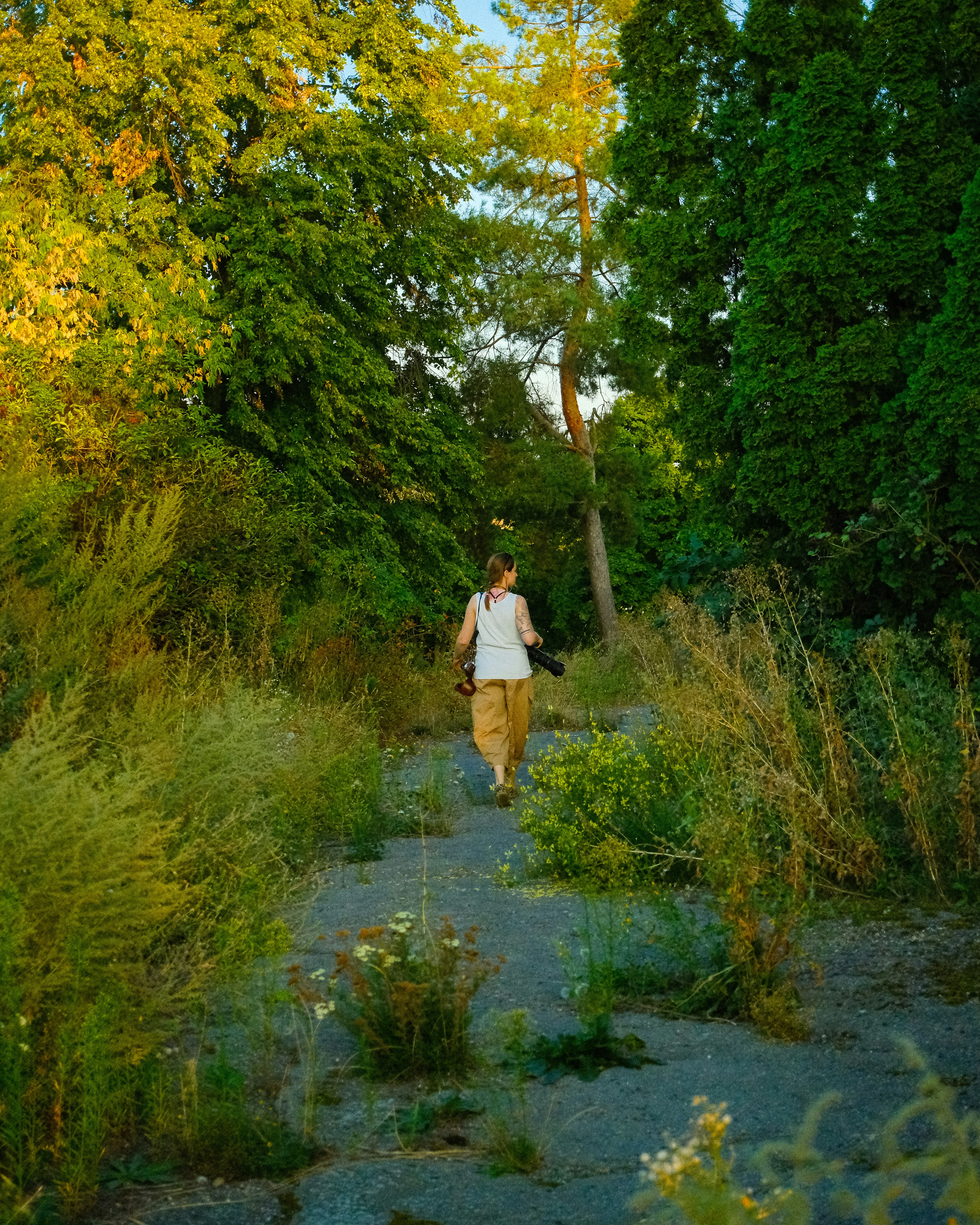 Woman walking on overgrown path in lush green forest