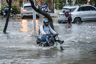 Man rides motorcycle through flooded street