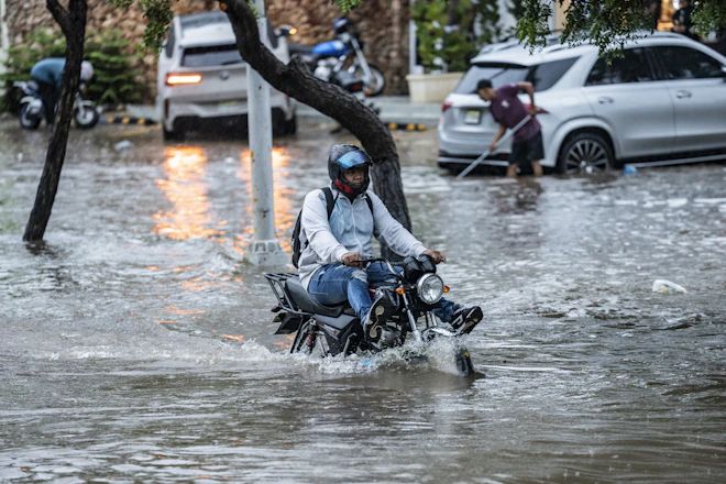 Man rides motorcycle through flooded street