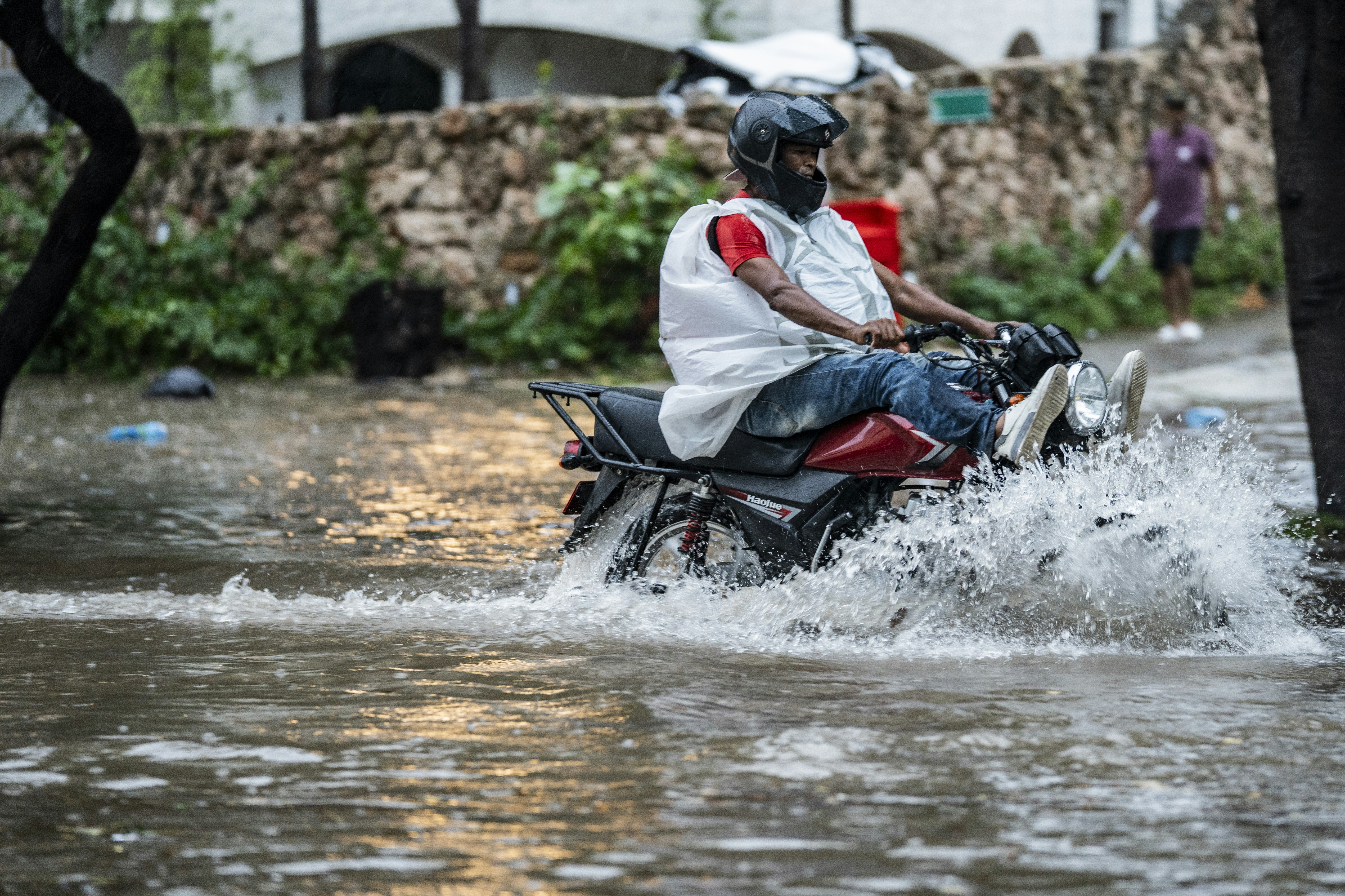 Man rides motorcycle through flooded street