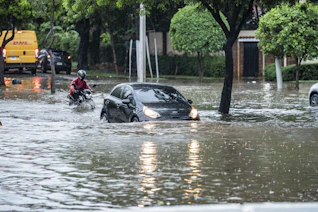 Cars driving through a flooded street during a storm.