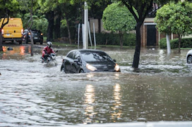 Cars driving through a flooded street during a storm.