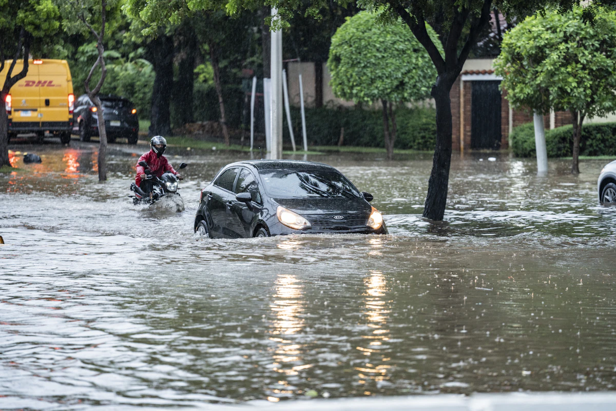 Mobil melintasi jalan yang tergenang banjir saat badai