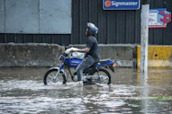 Man rides motorcycle through flooded street
