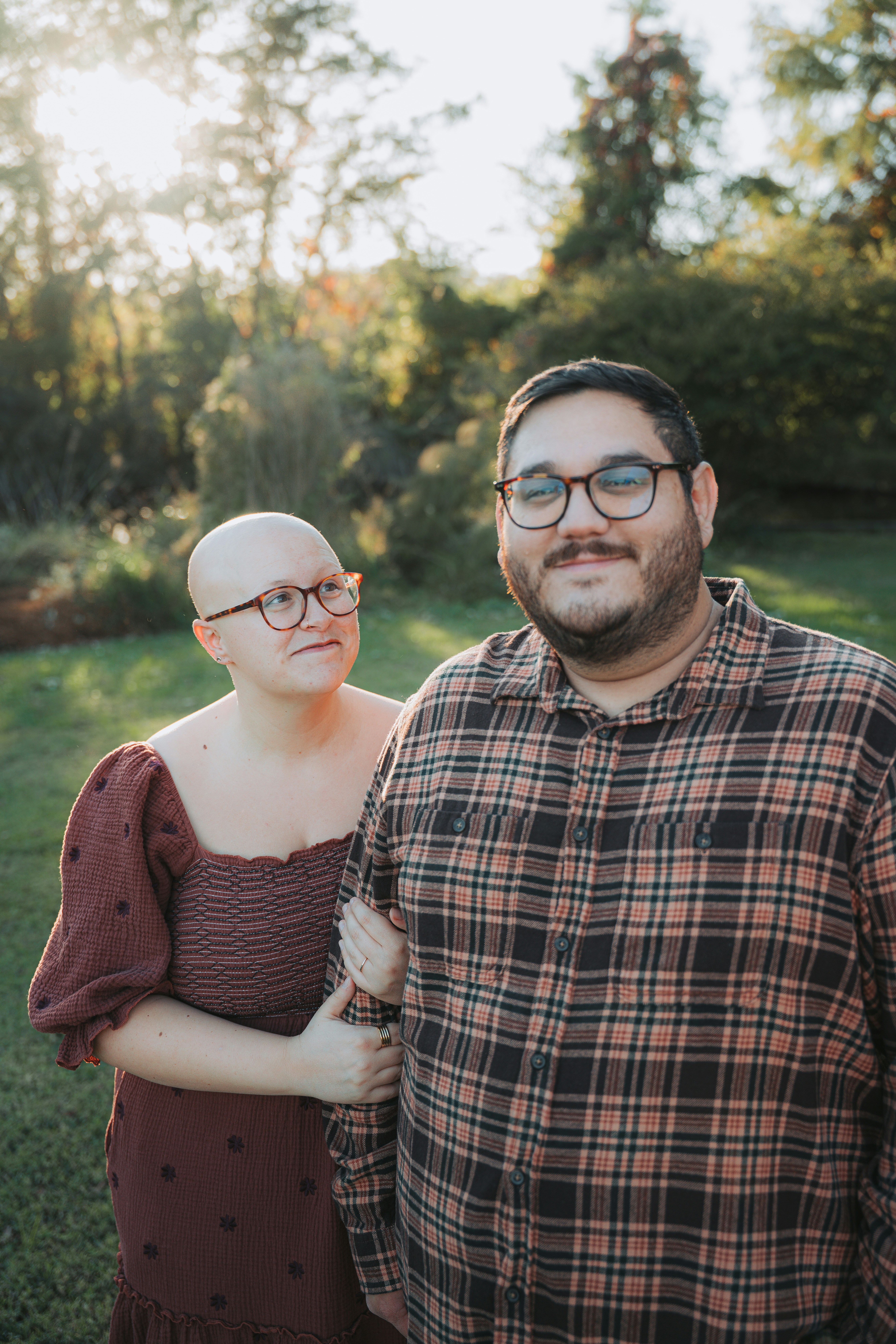 Couple standing together outdoors with trees behind them