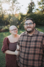 Couple standing together outdoors with trees behind them