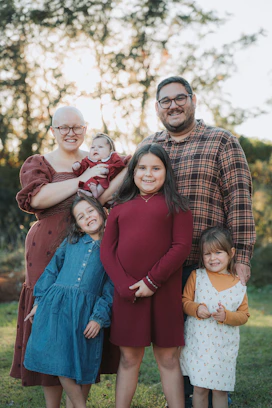 A happy family of six posing outdoors in sunlight