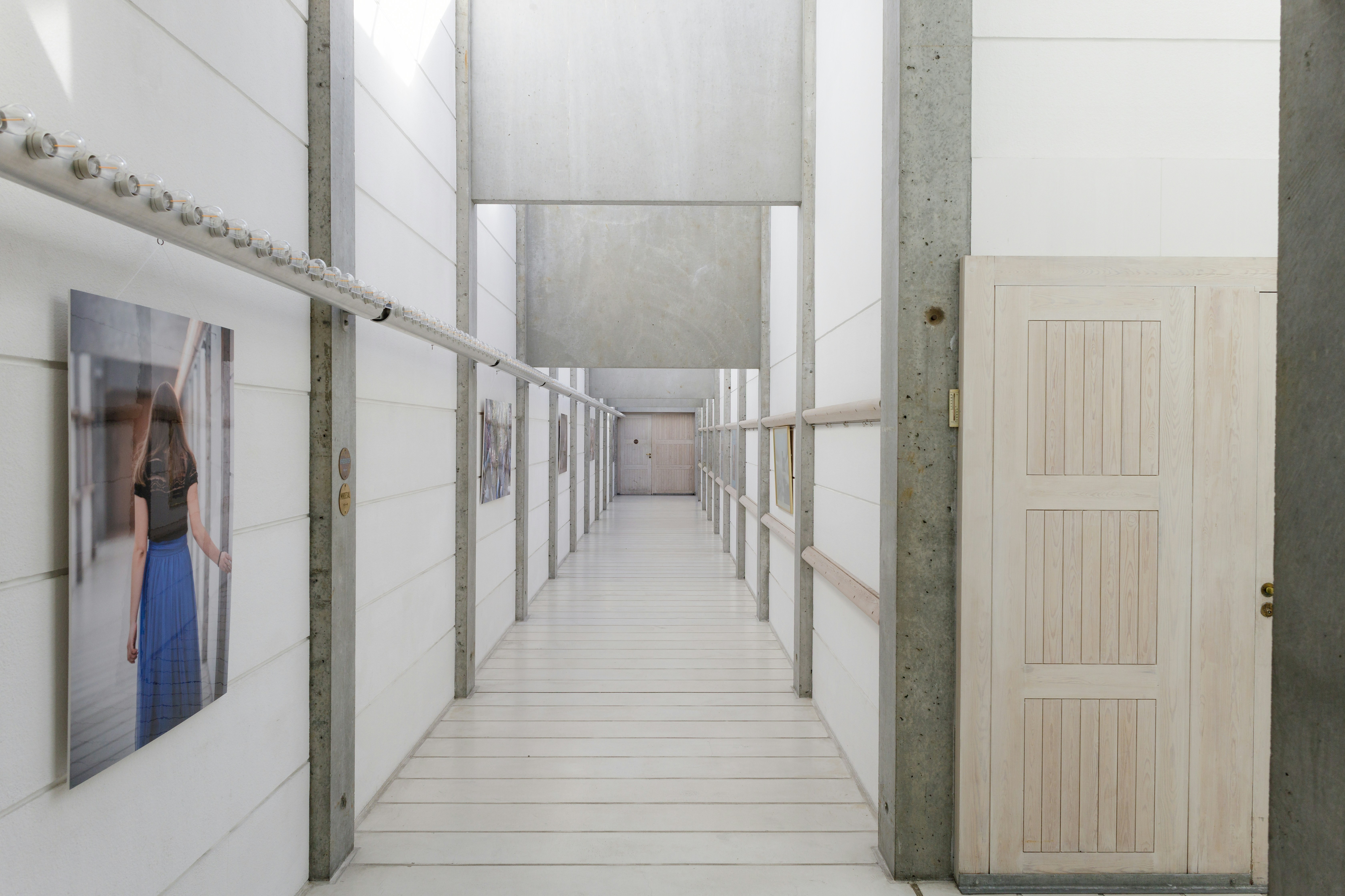 Long, minimalist hallway with doors and artwork.