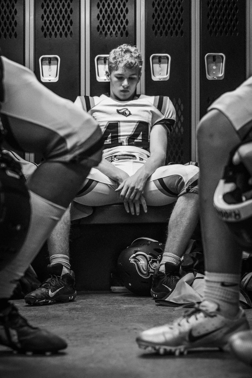 Young football player sits in locker room