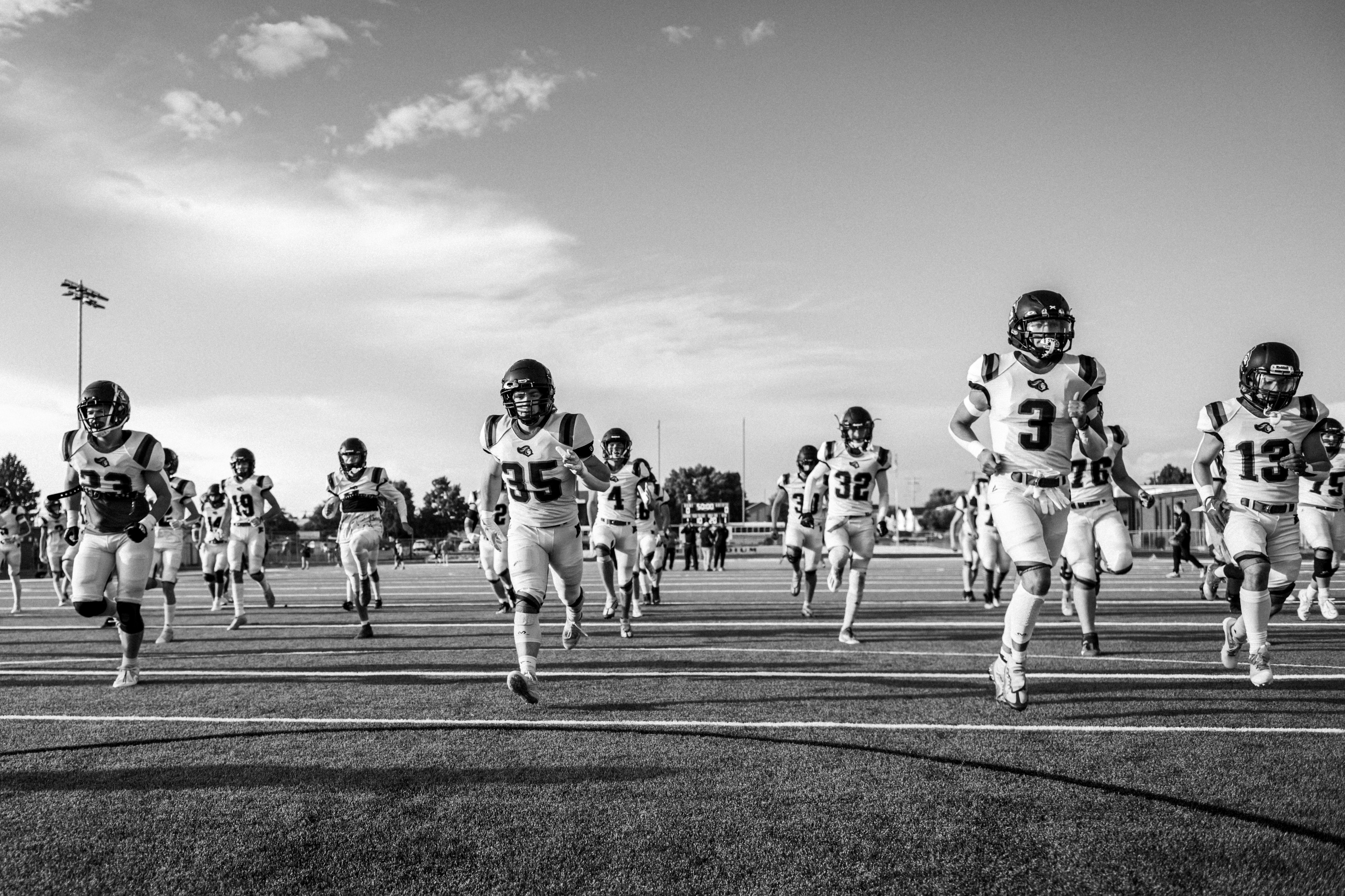 a high school football team practices sprint warmps before practice
