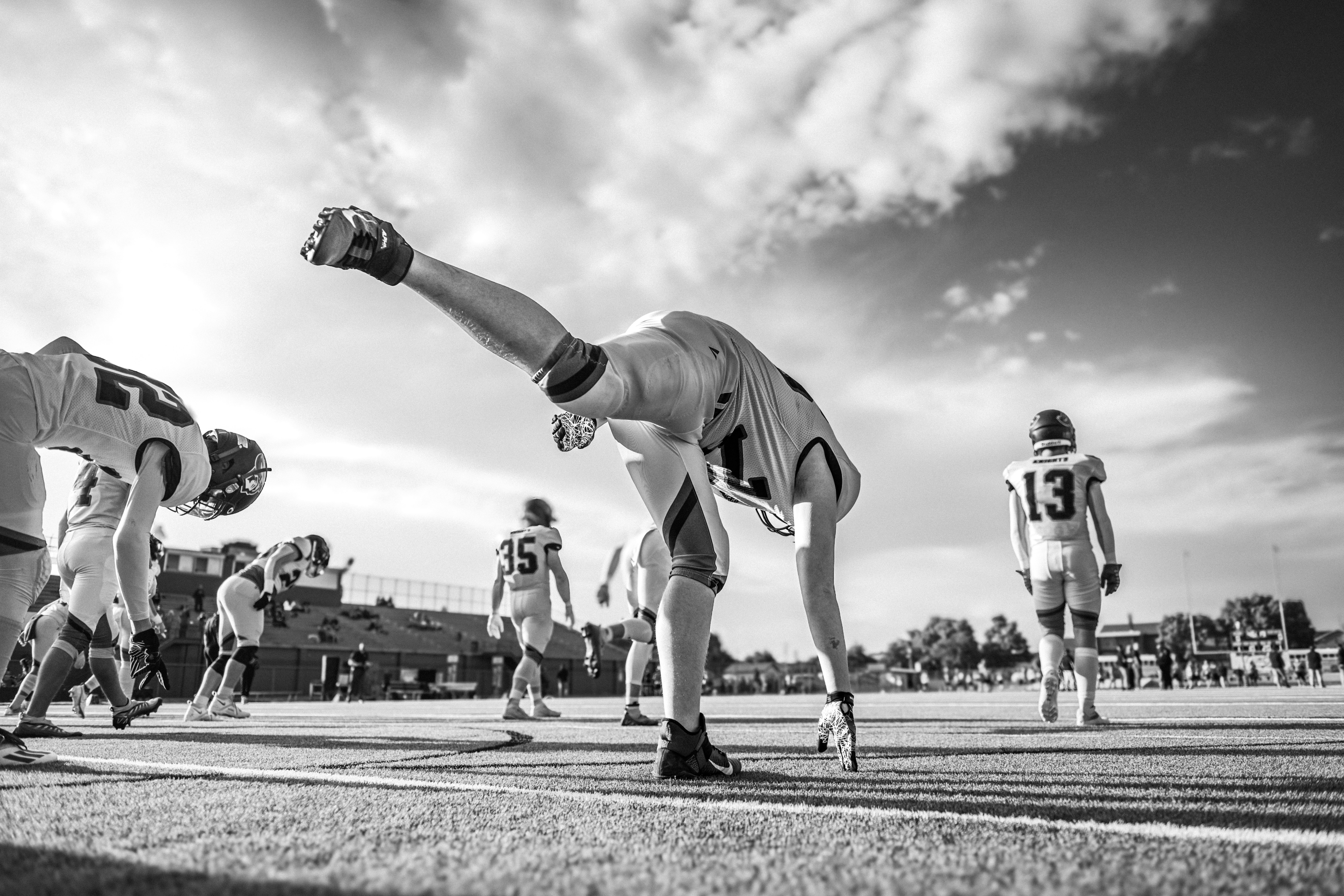 American football players stretching on field during game.