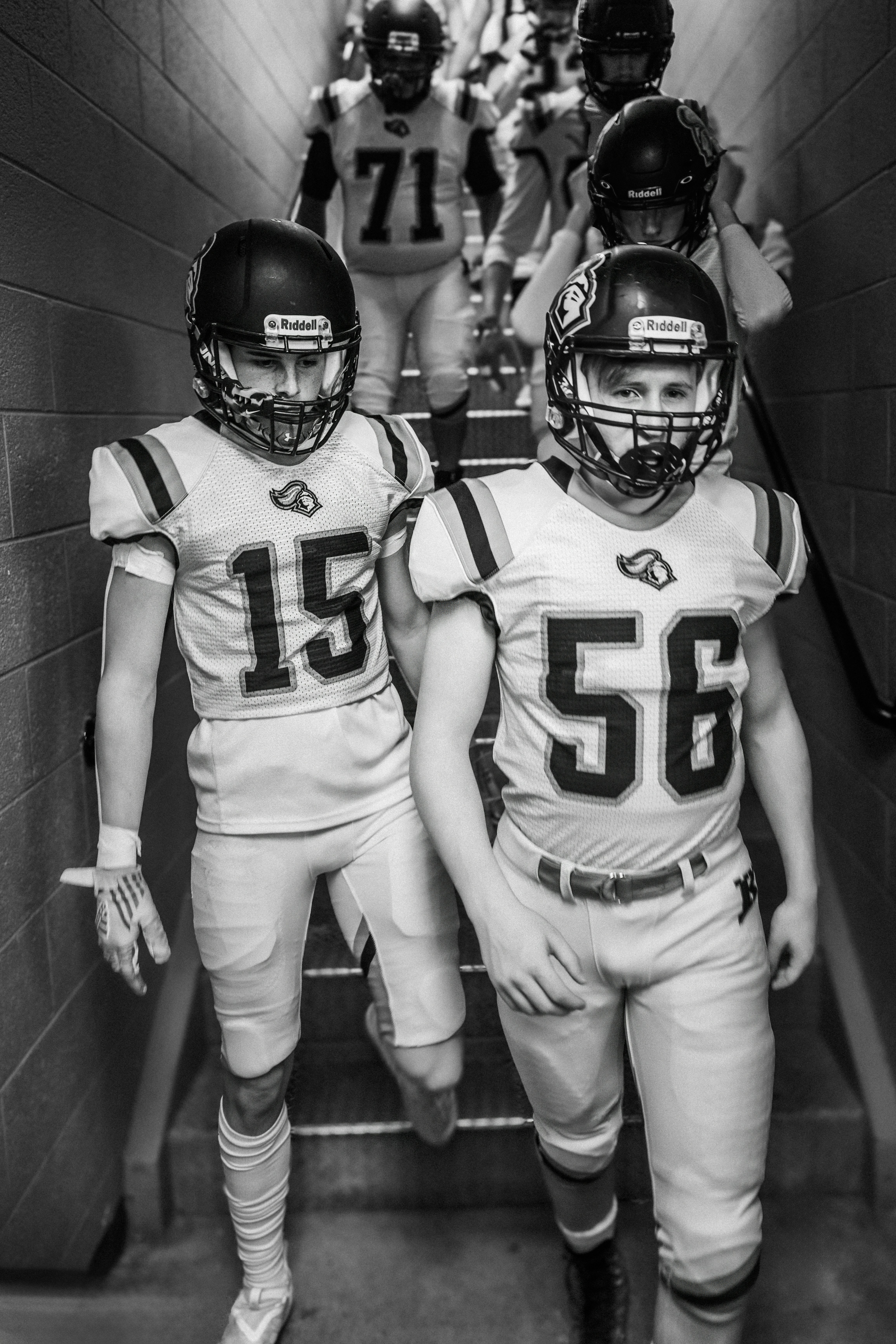 Football players in uniform walking down stairs.
