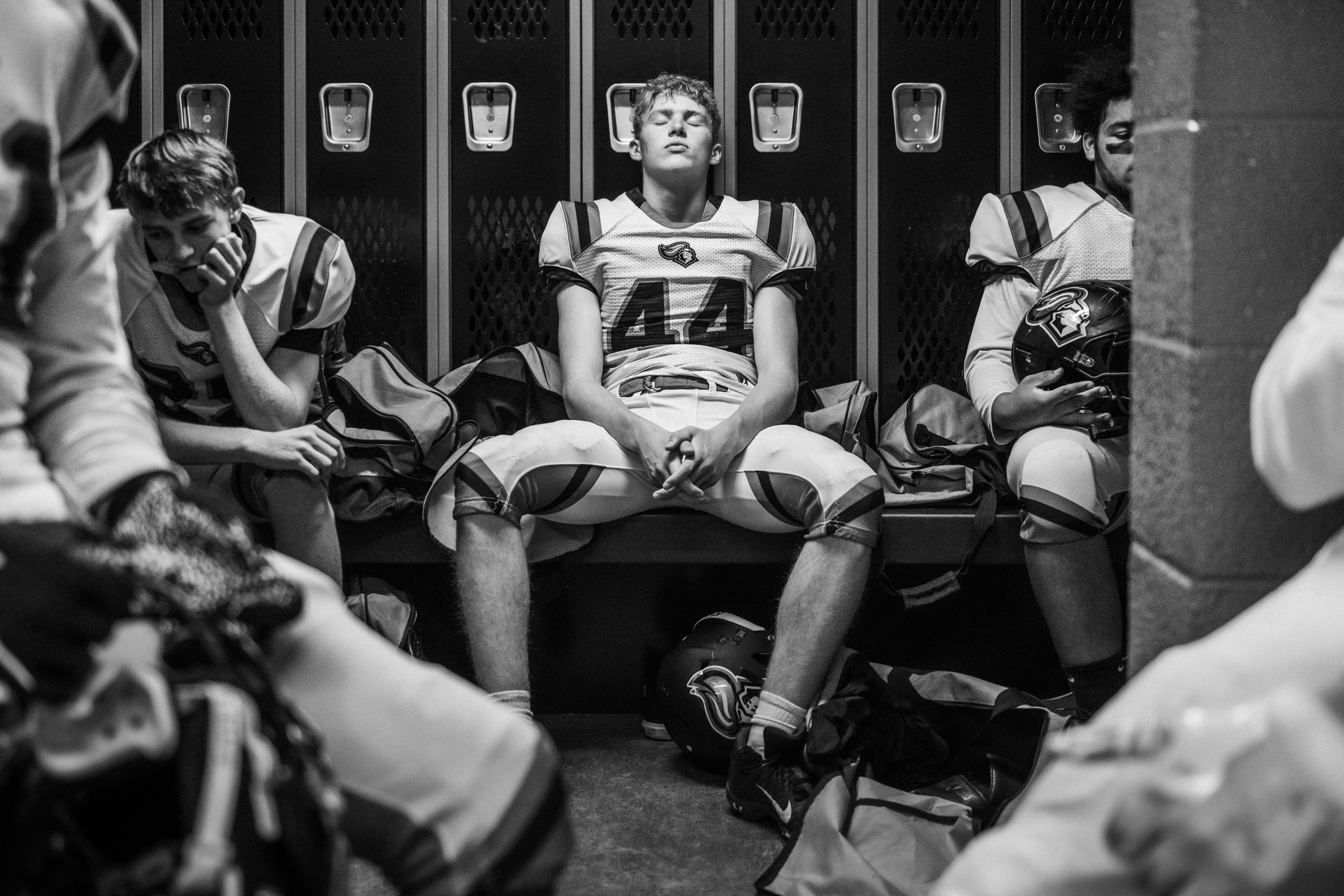 Football players sitting in a locker room.