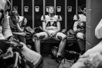 Football players sitting in a locker room.