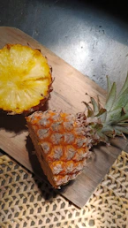 A pineapple cut in half on a wooden board