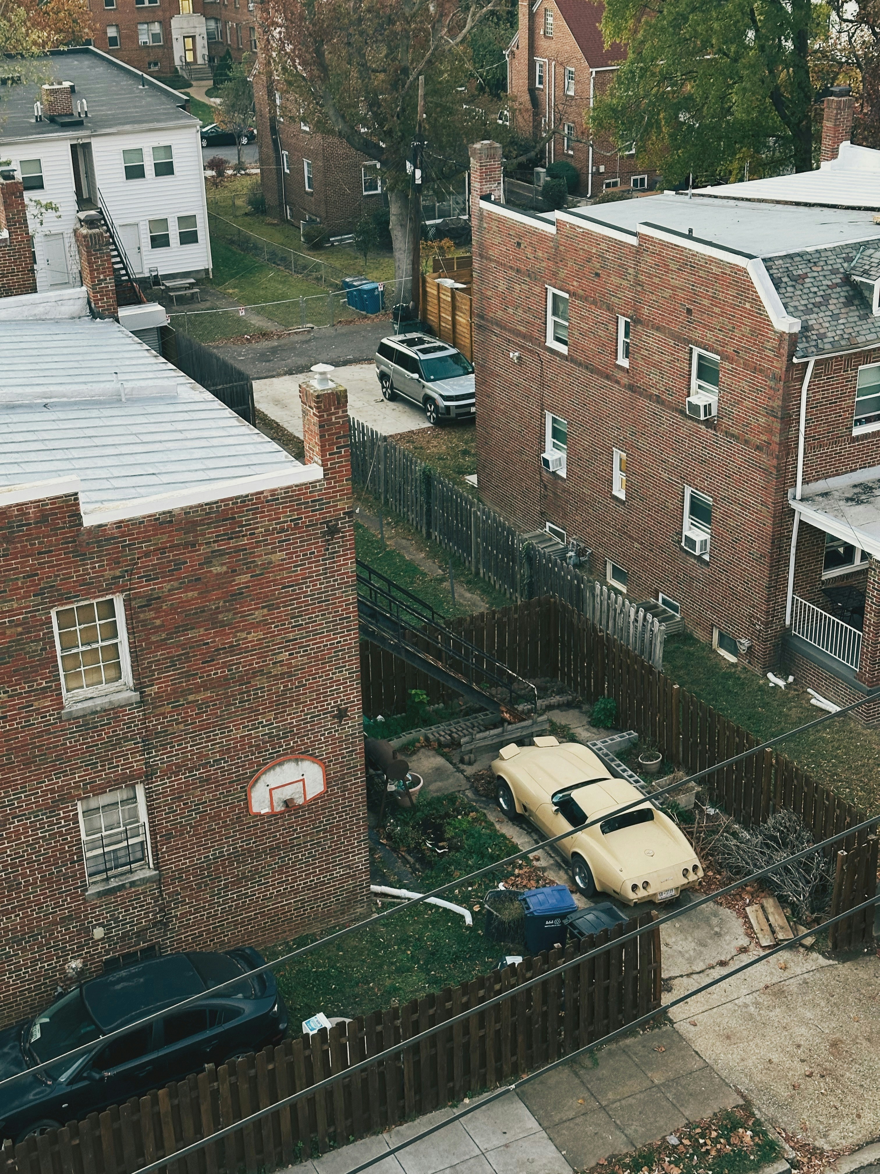 フェンスで囲まれた裏庭に駐車された黄色いスポーツカー。