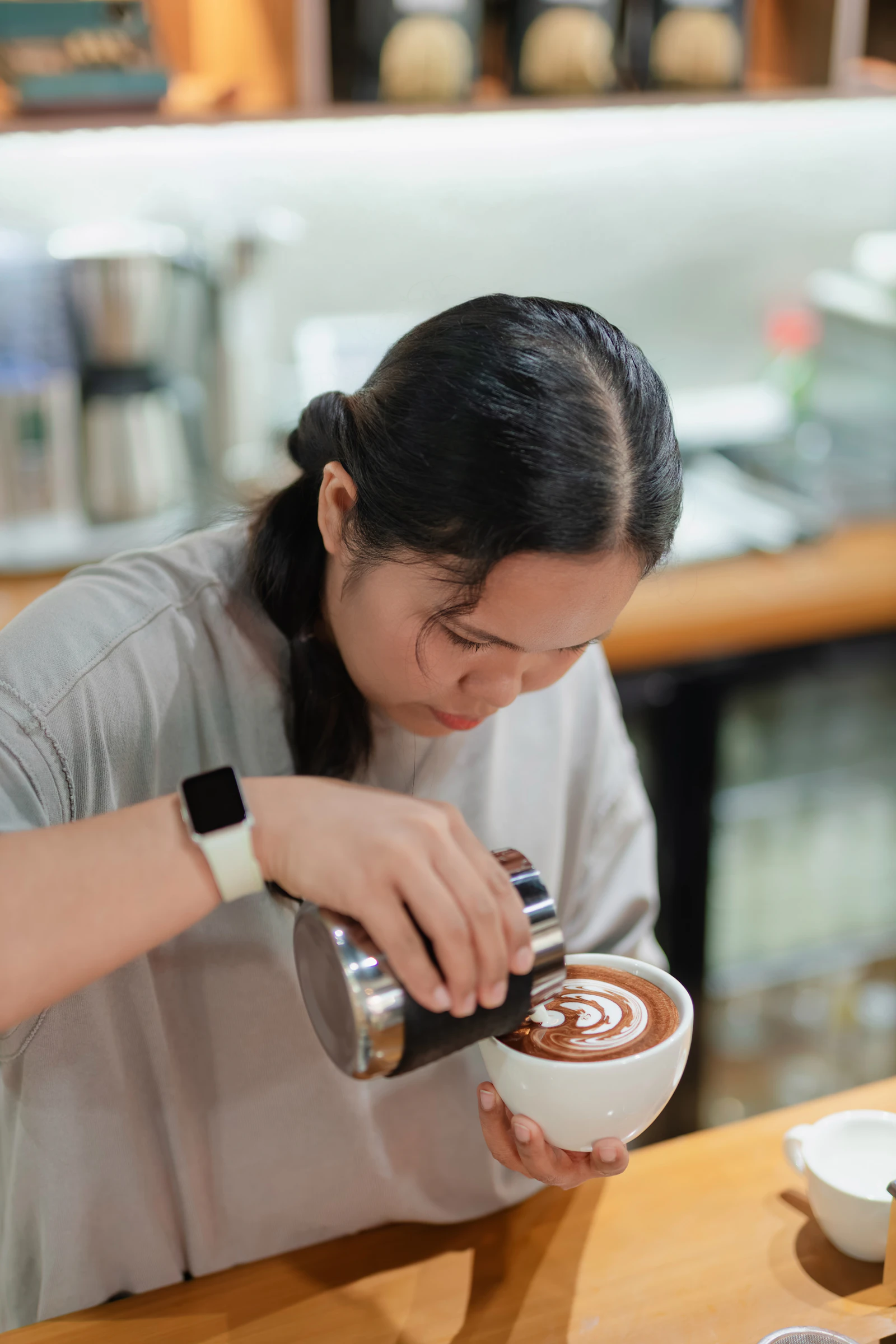 Barista hand-pouring coffee, latte art in progress