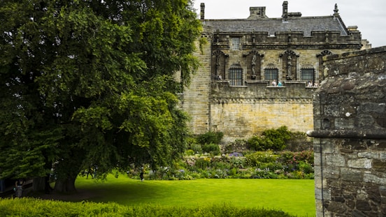 Historic stone building with a large tree and garden.