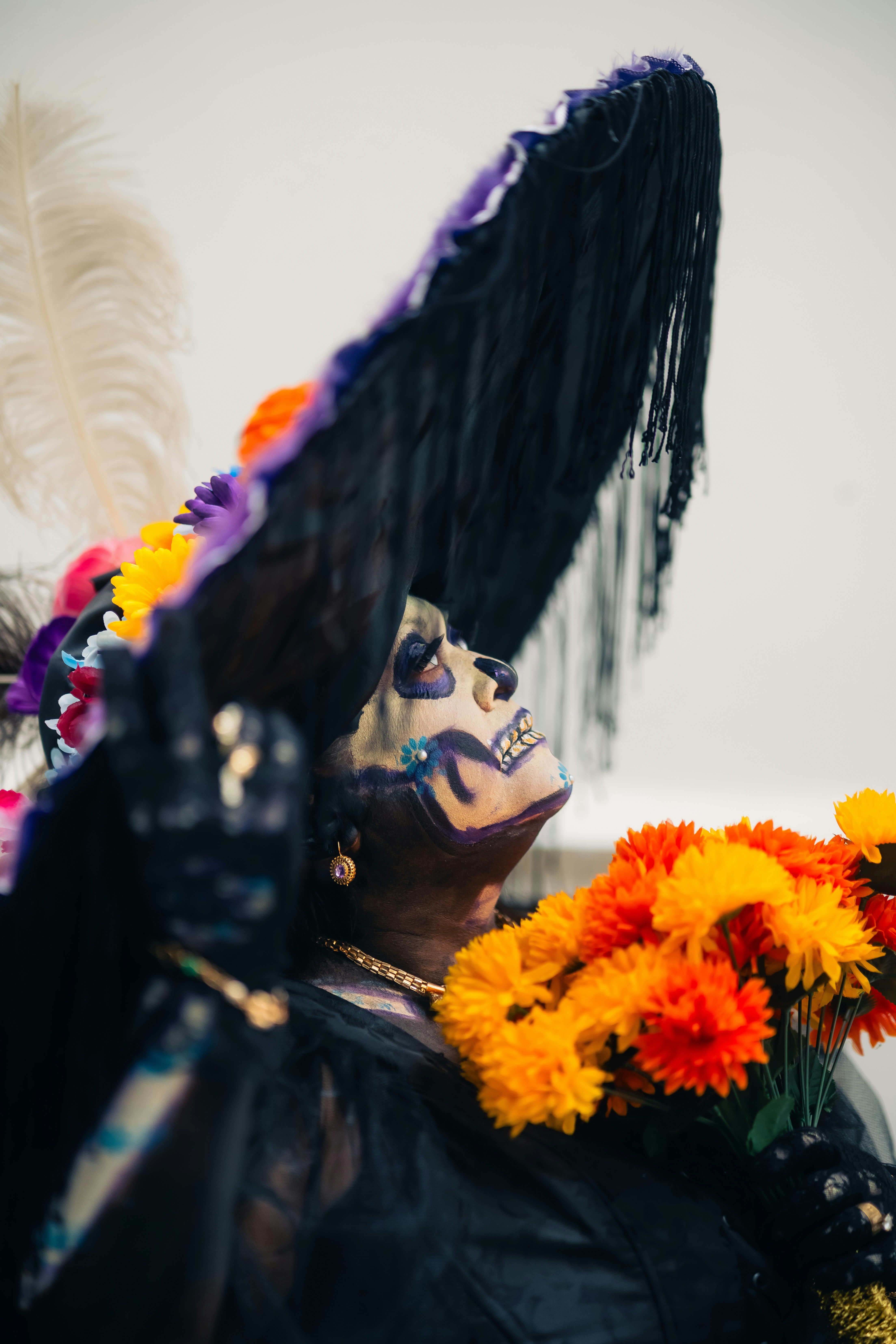 Pessoa na pintura da cara do crânio e no grande chapéu com flores