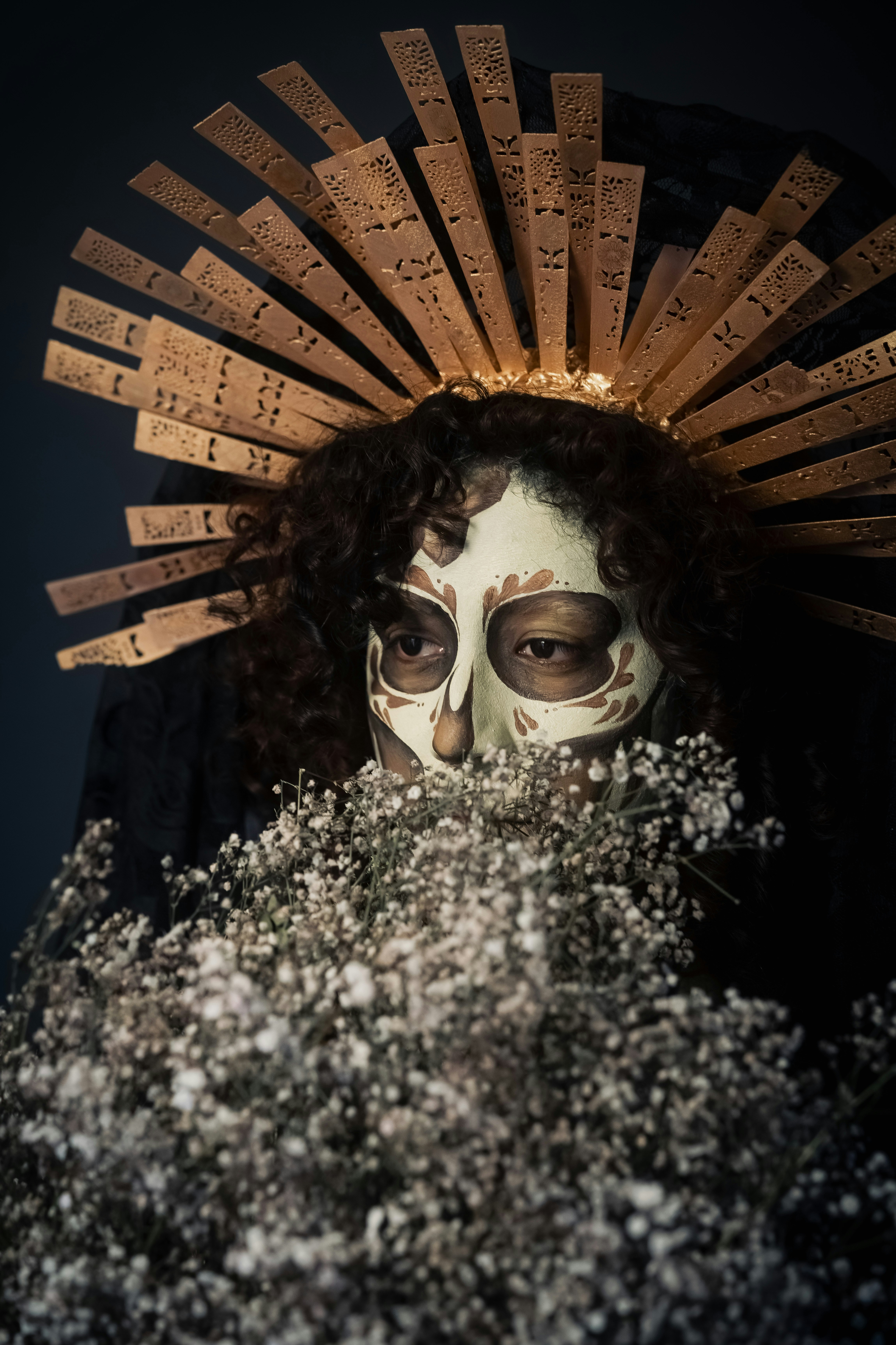 Mulher na composição do crânio com cocar e flores dourados