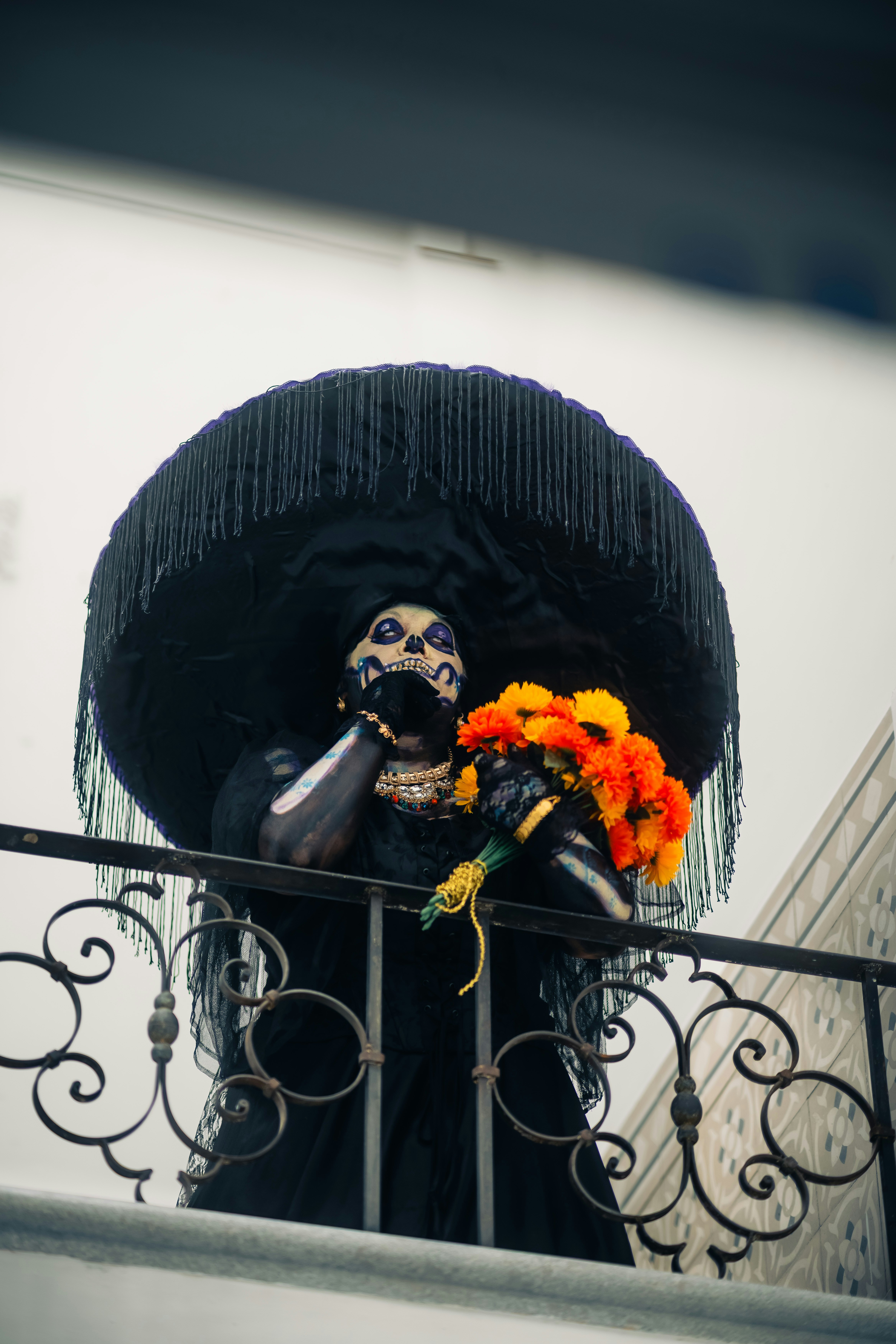 Pessoa na composição de esqueleto que guarda flores alaranjadas