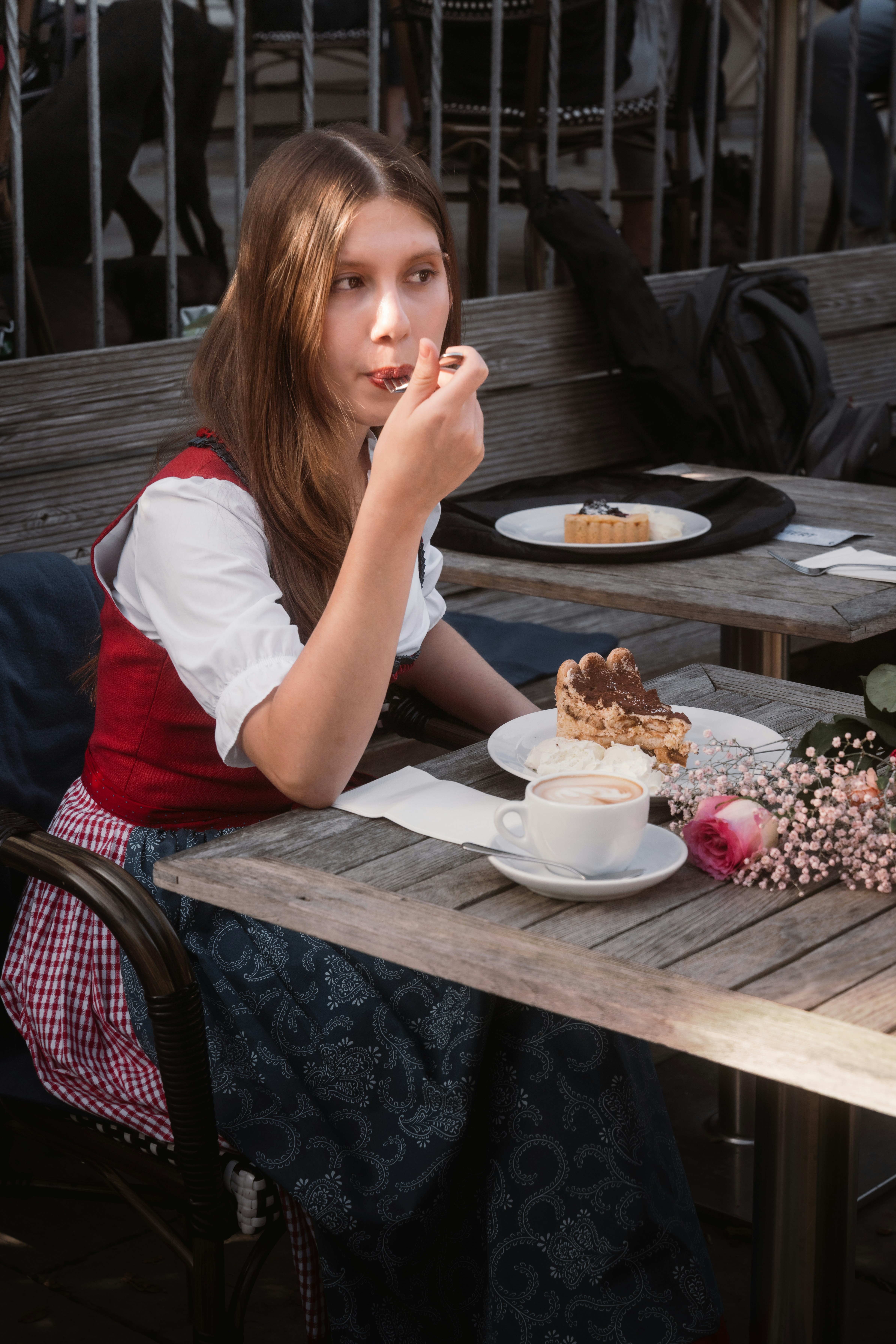 Young woman in traditional dress eating dessert at cafe