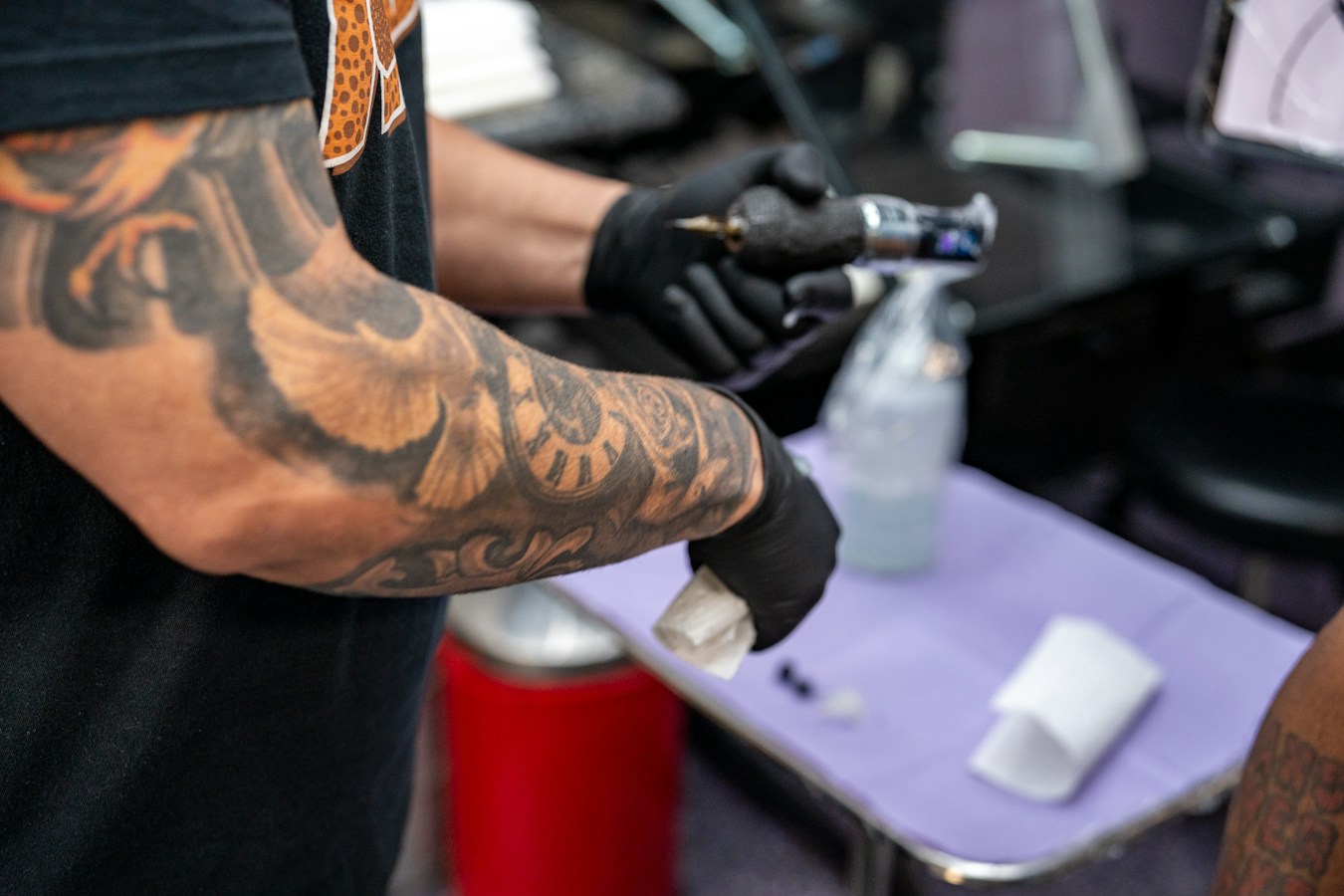 Un tatuador con guantes negros preparando el equipo antes de una sesión