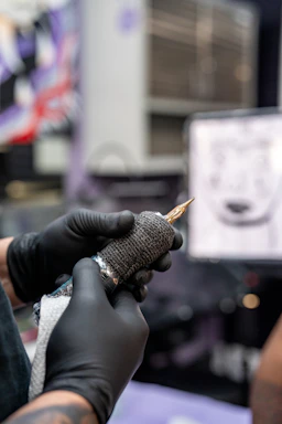 Tattoo artist preparing machine with gloved hands