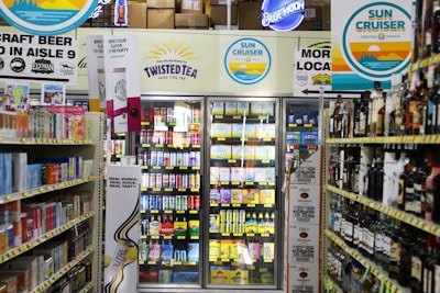 Refrigerated drinks and alcoholic beverages on shelves.