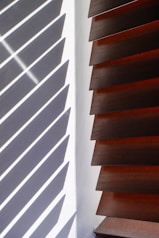 Wooden blinds casting striped shadows on wall