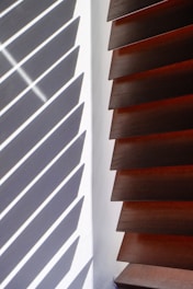 Wooden blinds casting striped shadows on wall