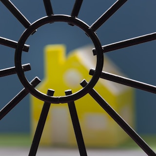Yellow toy house seen through metal grate