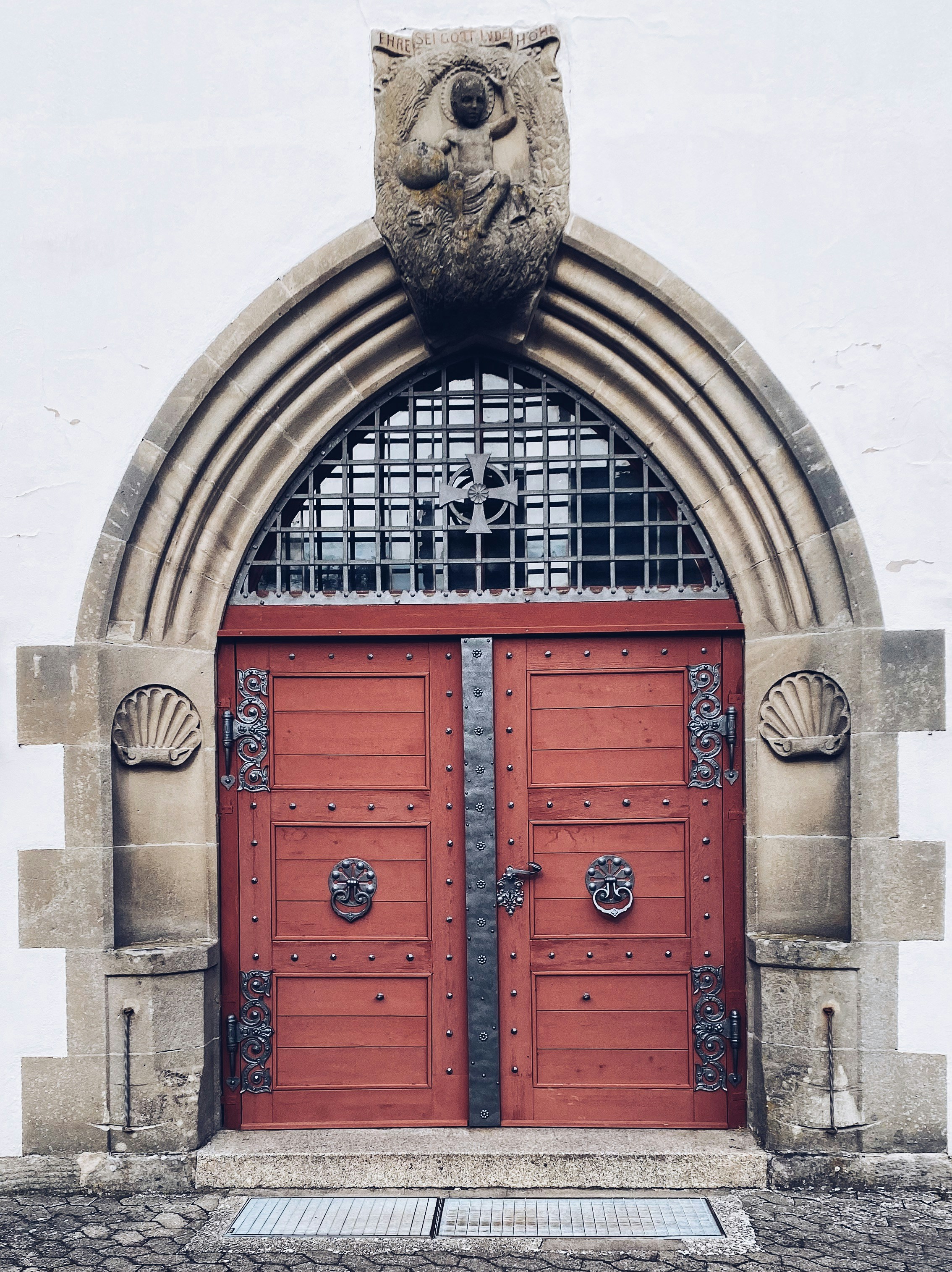 Ornate red wooden doors with stone archway and carvings