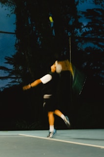 A tennis player hitting a ball at night.
