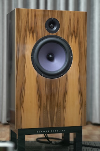 Wooden speaker with a black stand and purple cone.