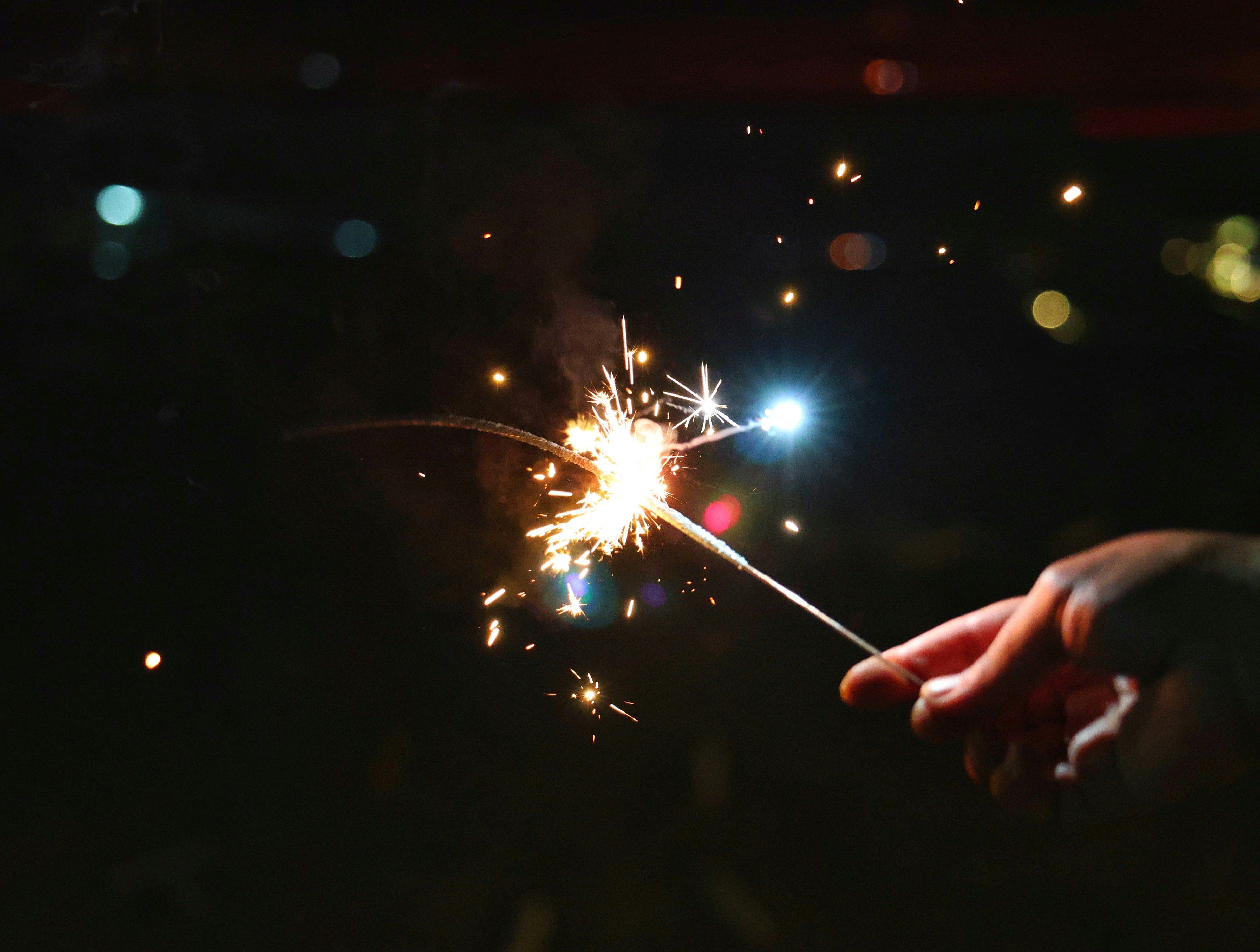 Hand holding a lit sparkler at night