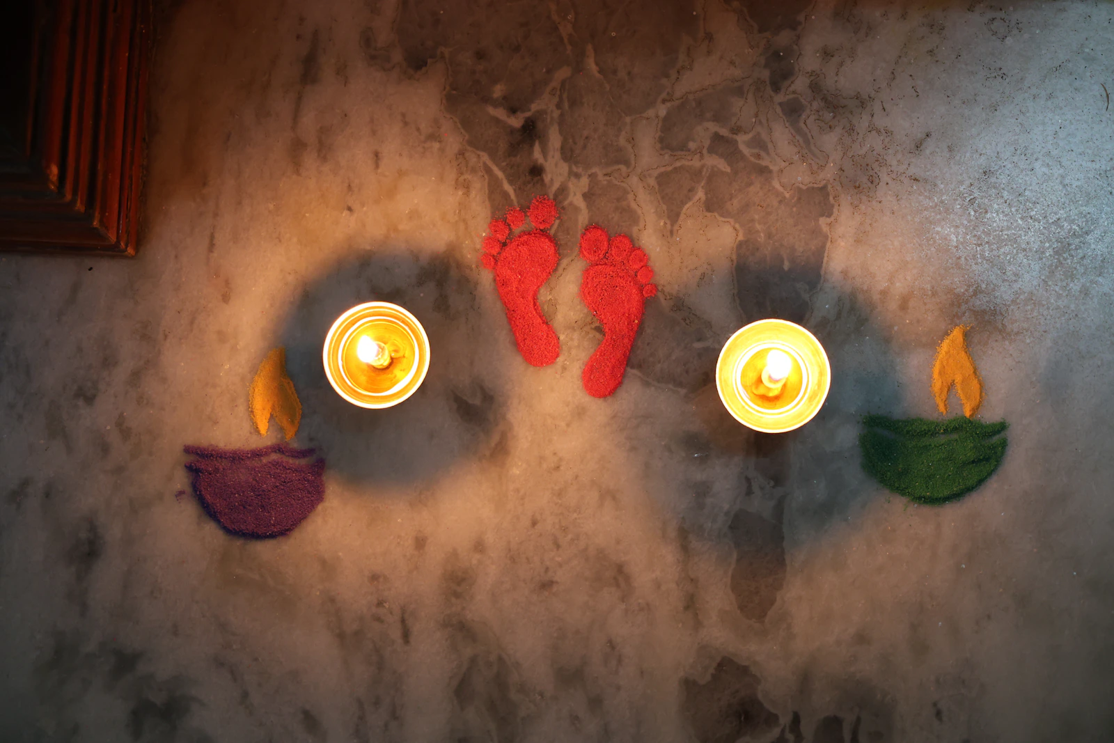Two diyas and a pair of Lakshmi footprints drawn on the floor.