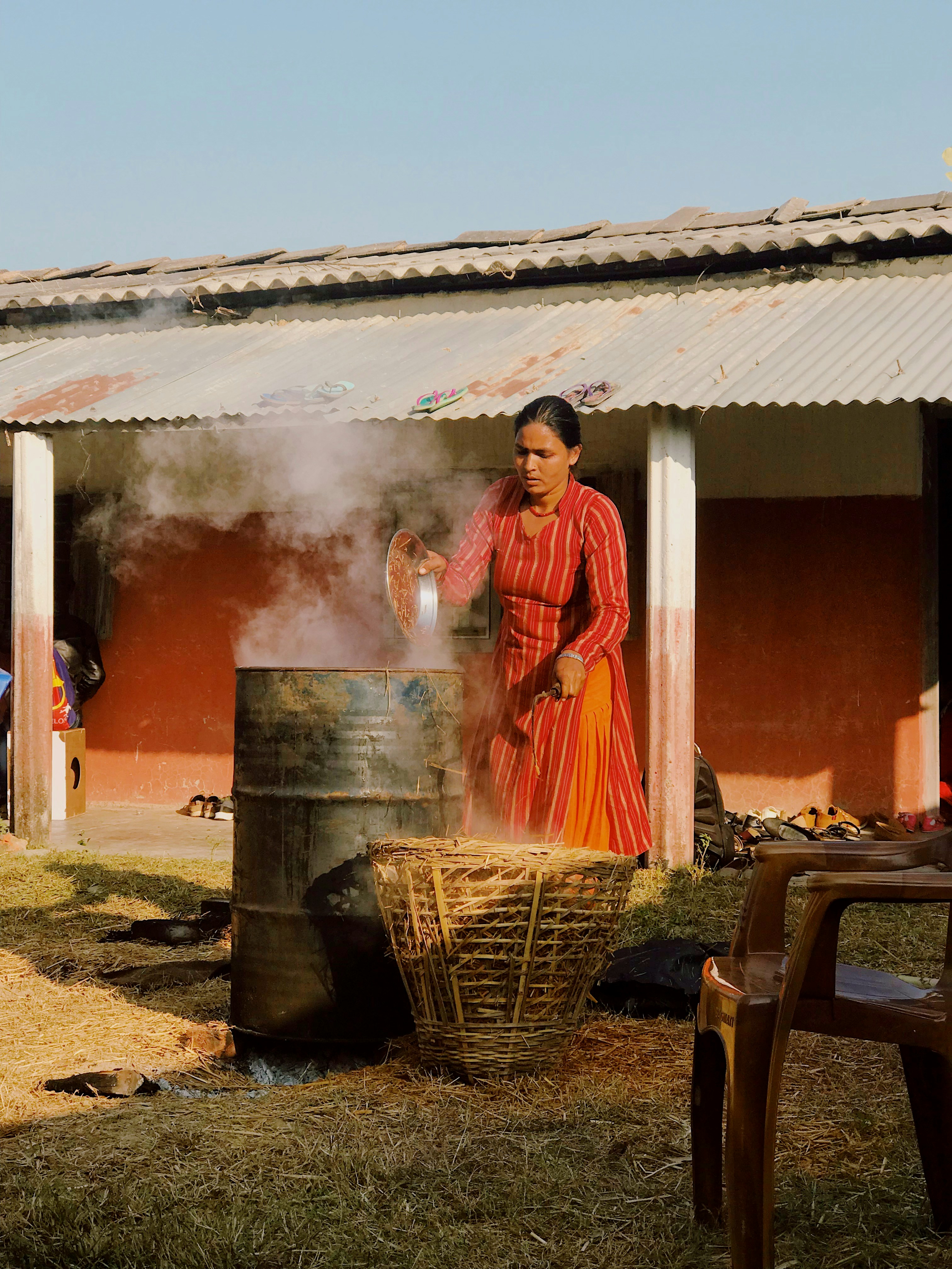 Woman cooking in a large metal pot outdoors.